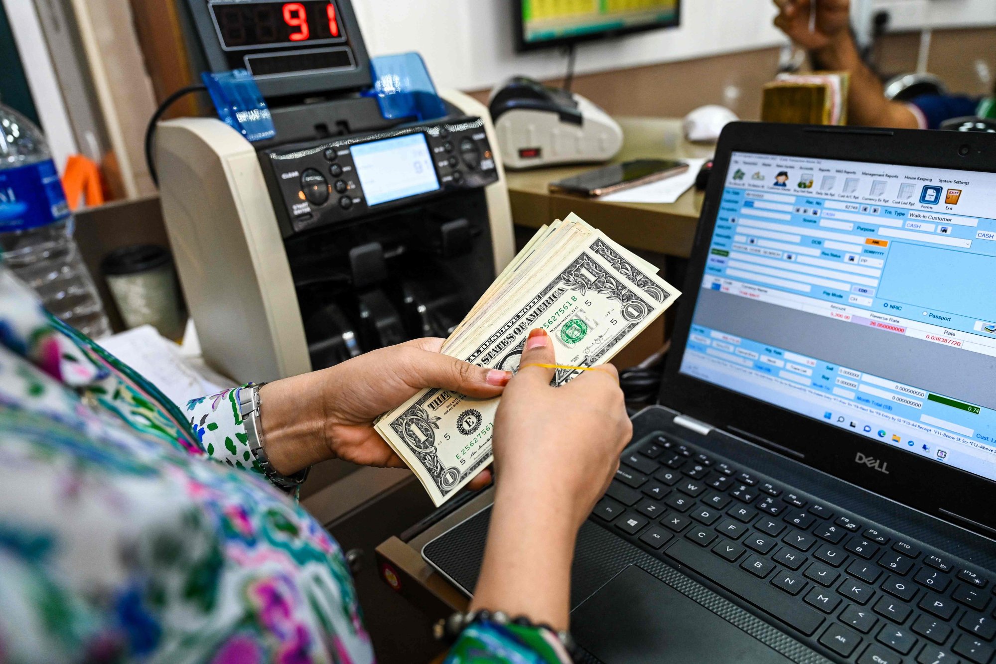 A teller counts US dollars at a money changing booth at Raffles Place in Singapore on October 6. Photo: AFP