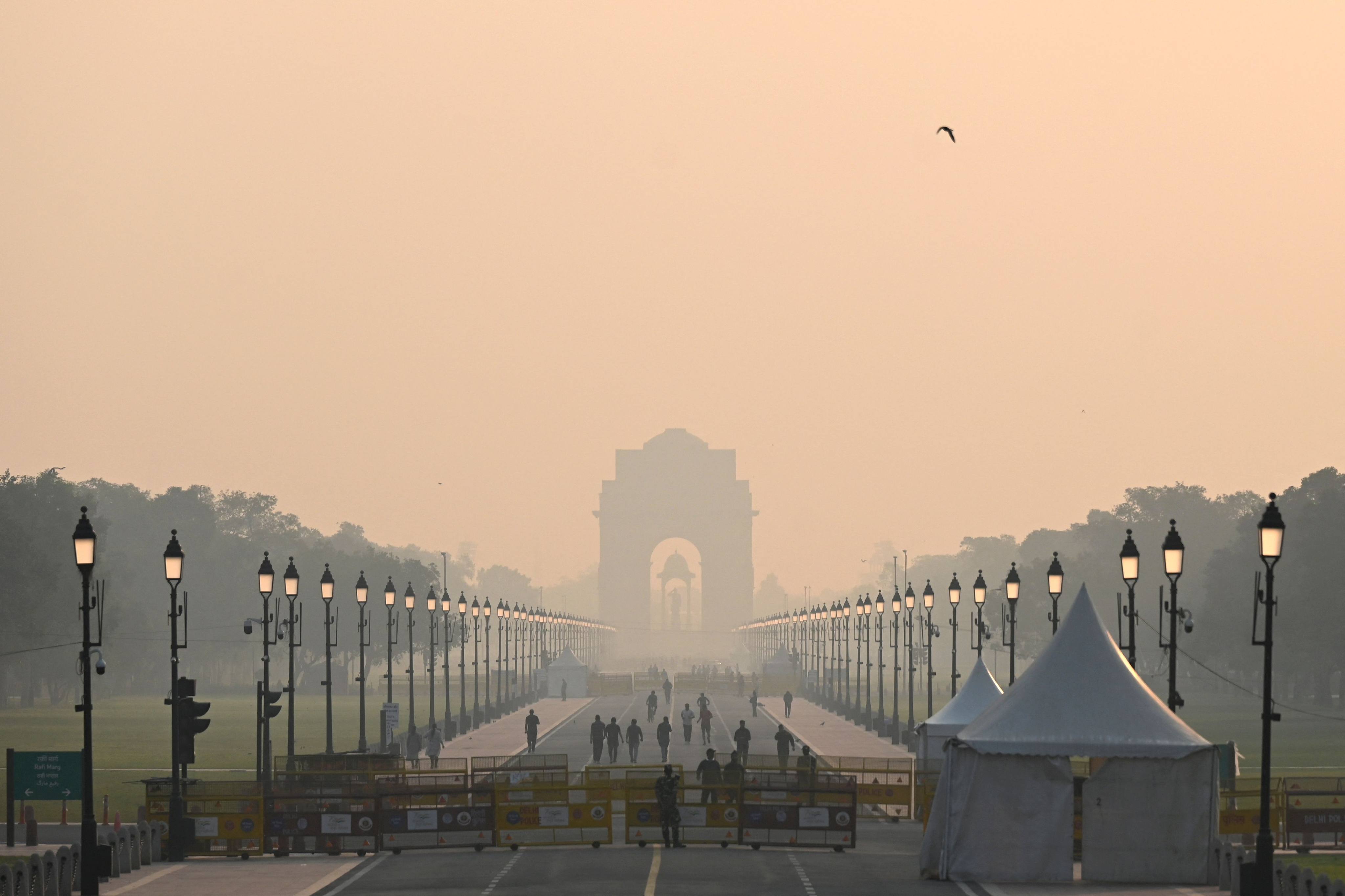 People walk along a road near India Gate amid smoggy conditions in New Delhi on October 25 after Diwali revellers defied a firecracker ban to celebrate the annual Hindu festival. Photo: AFP