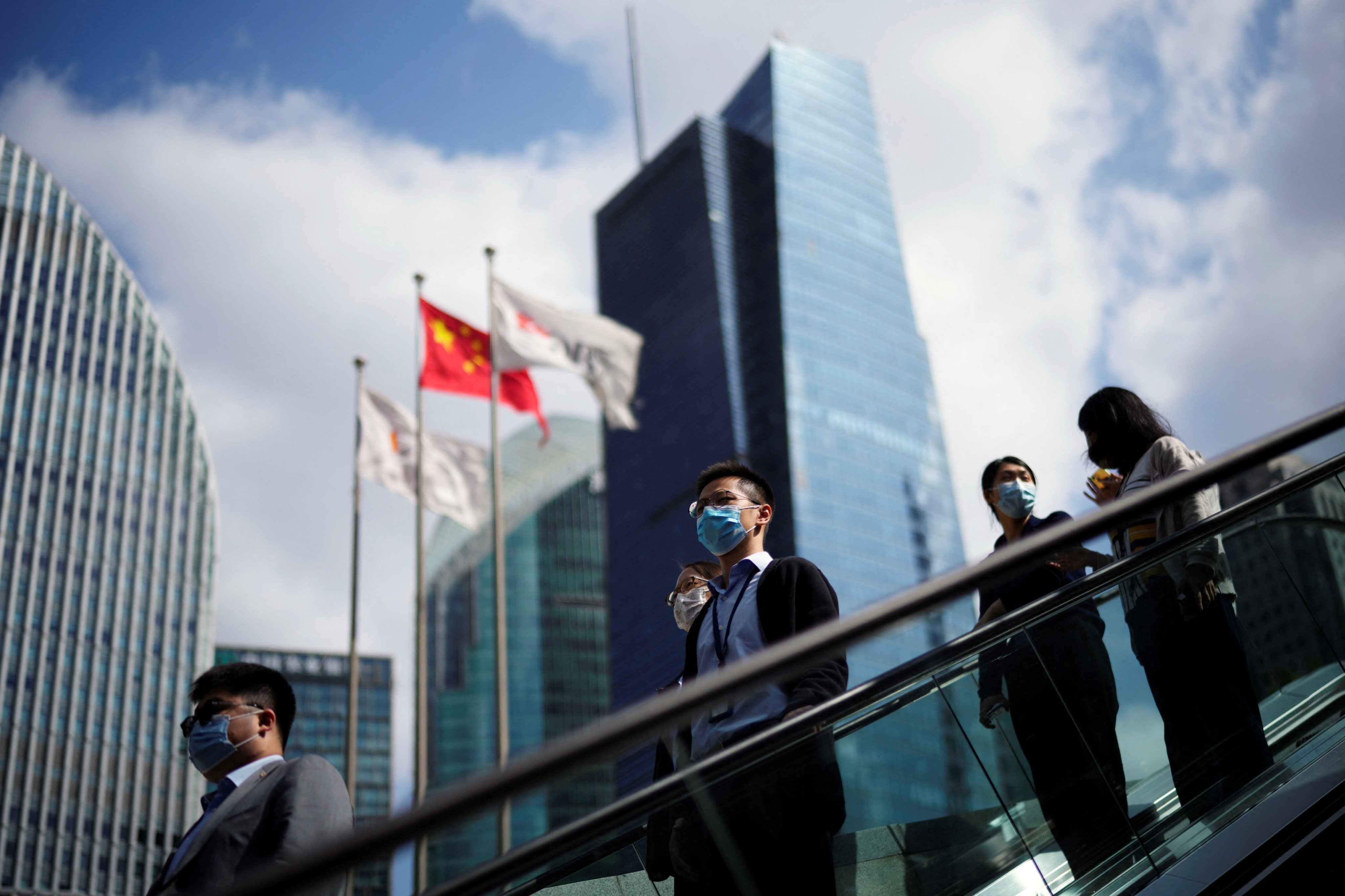 People ride an escalator past office towers in the Lujiazui financial district of Shanghai on October 17. Photo: Reuters
