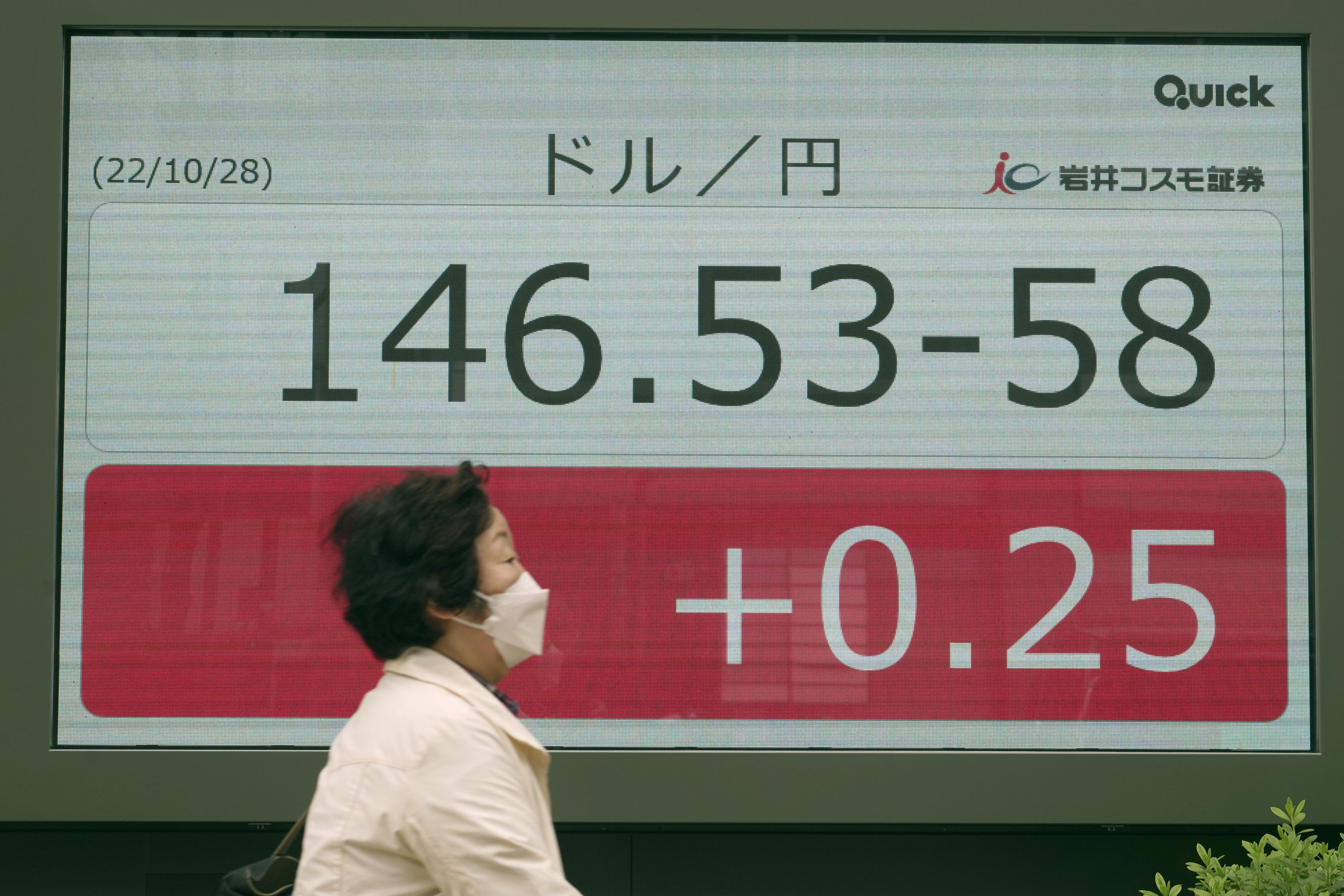 A pedestrian passes in front of an electronic stock board showing Japanese yen-US dollar conversion rate at a securities firm in Tokyo on October 28. A weakening of the yen against the dollar has amplified costs for imports. Photo: AP
