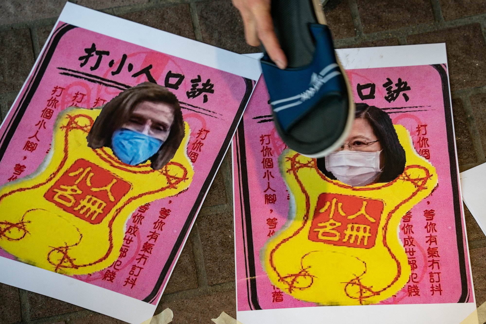 A pro-China supporter hits images of US House of Representatives Speaker Nancy Pelosi and Taiwan President Tsai Ing-wen with a shoe. File photo: TNS