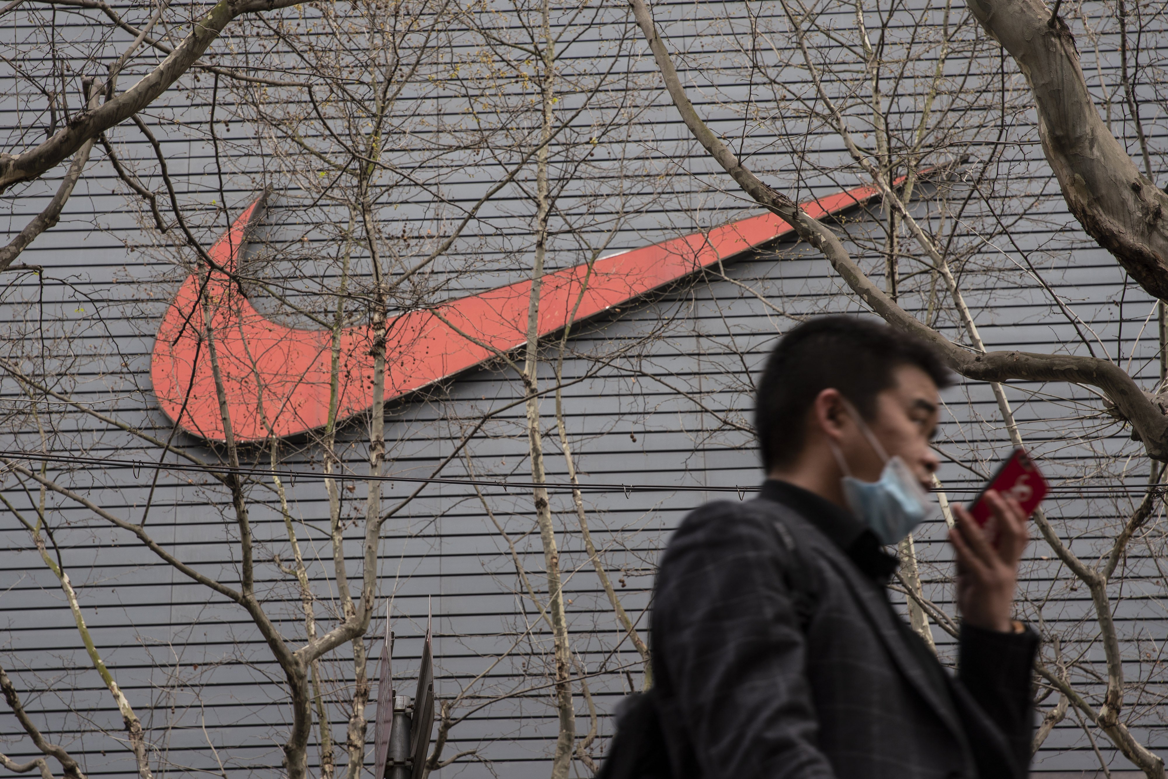 A pedestrian speaks into a smartphone outside a Nike store in Shanghai, March 26, 2021. Photo: Bloomberg