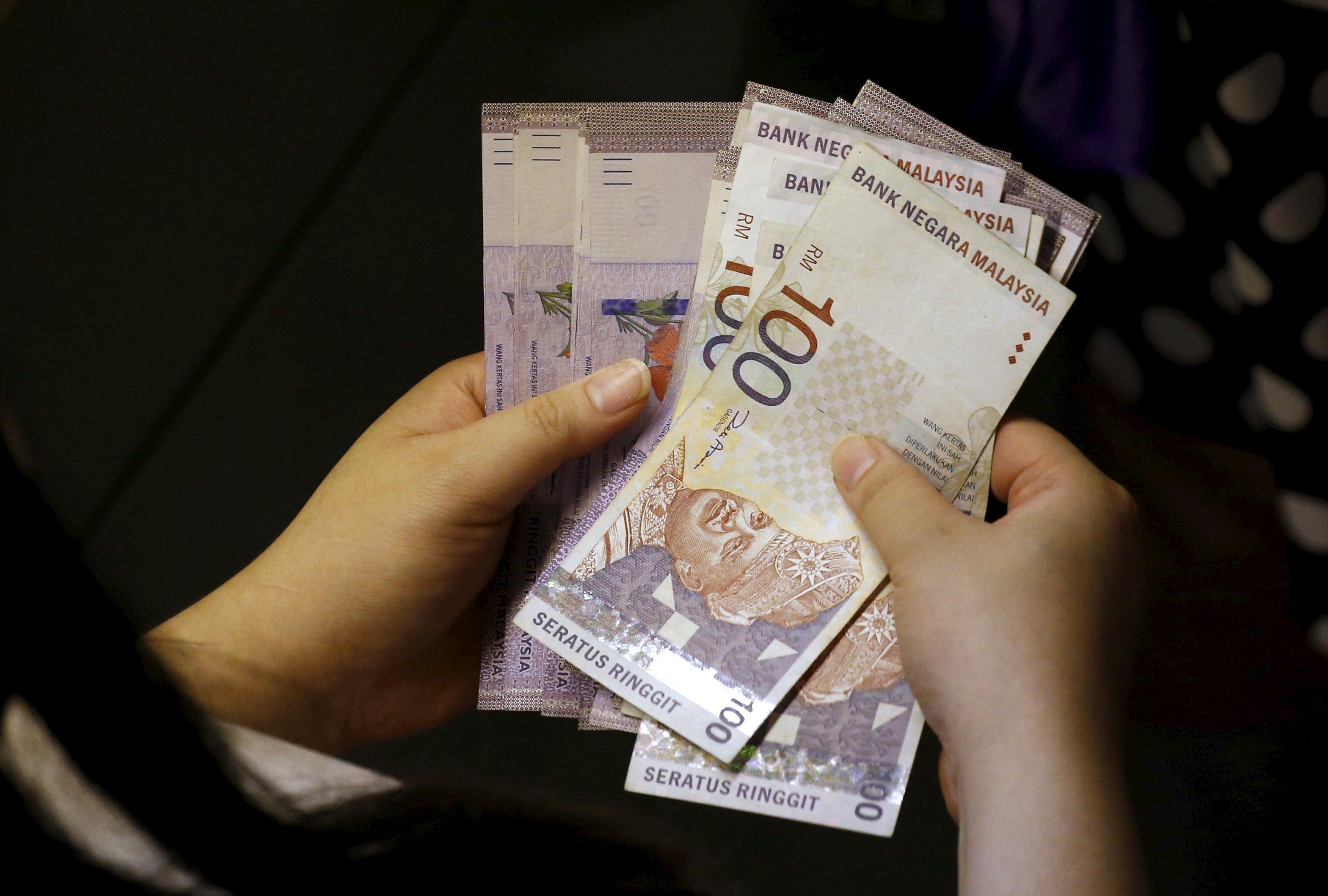 A woman counts her ringgit banknotes outside a money changer in Singapore. Photo: Reuters