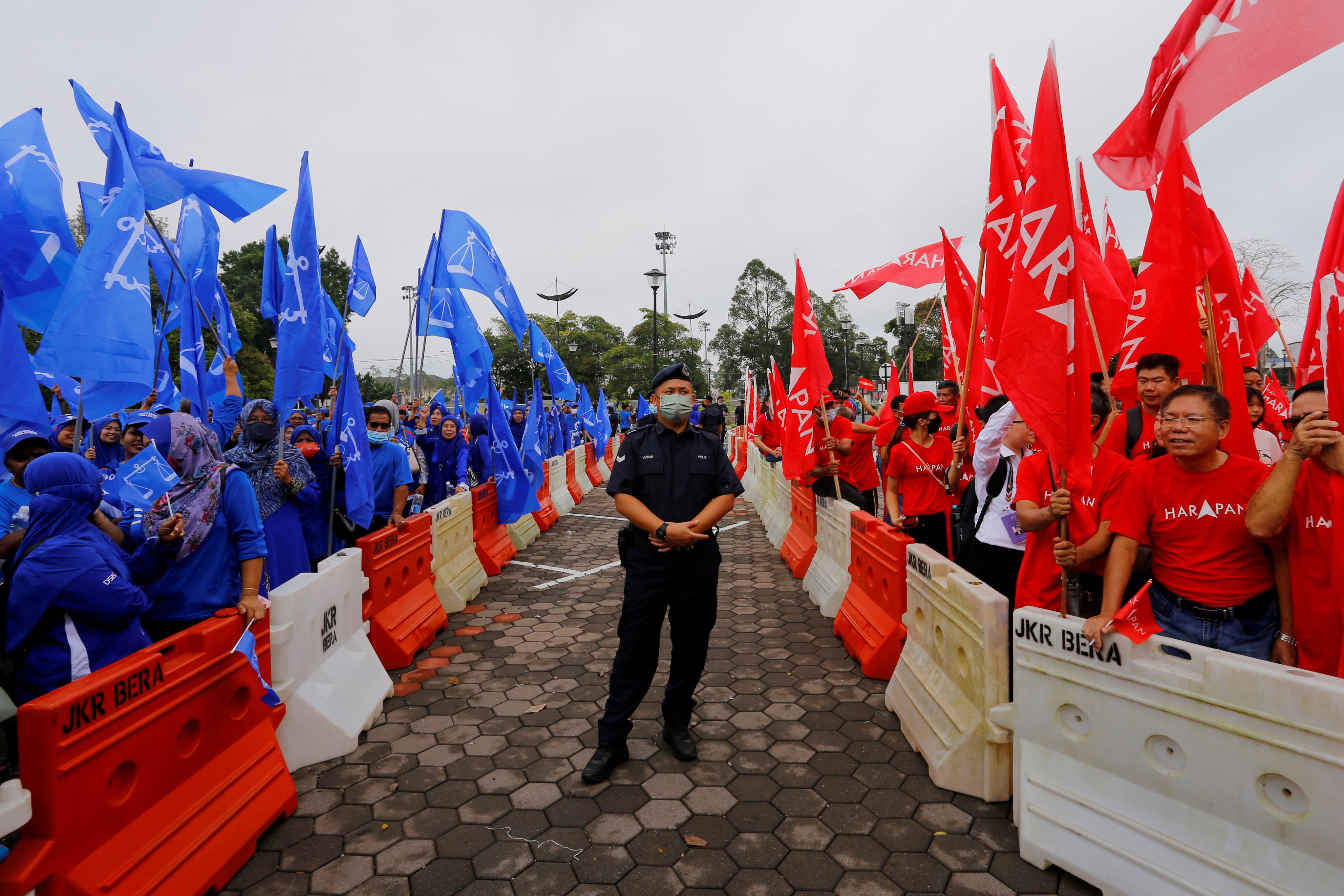 A policeman stands guard between rival groups of Barisan Nasional (left) and Pakatan Harapan supporters outside a nomination centre in Pahang on nomination day. Photo: Reuters