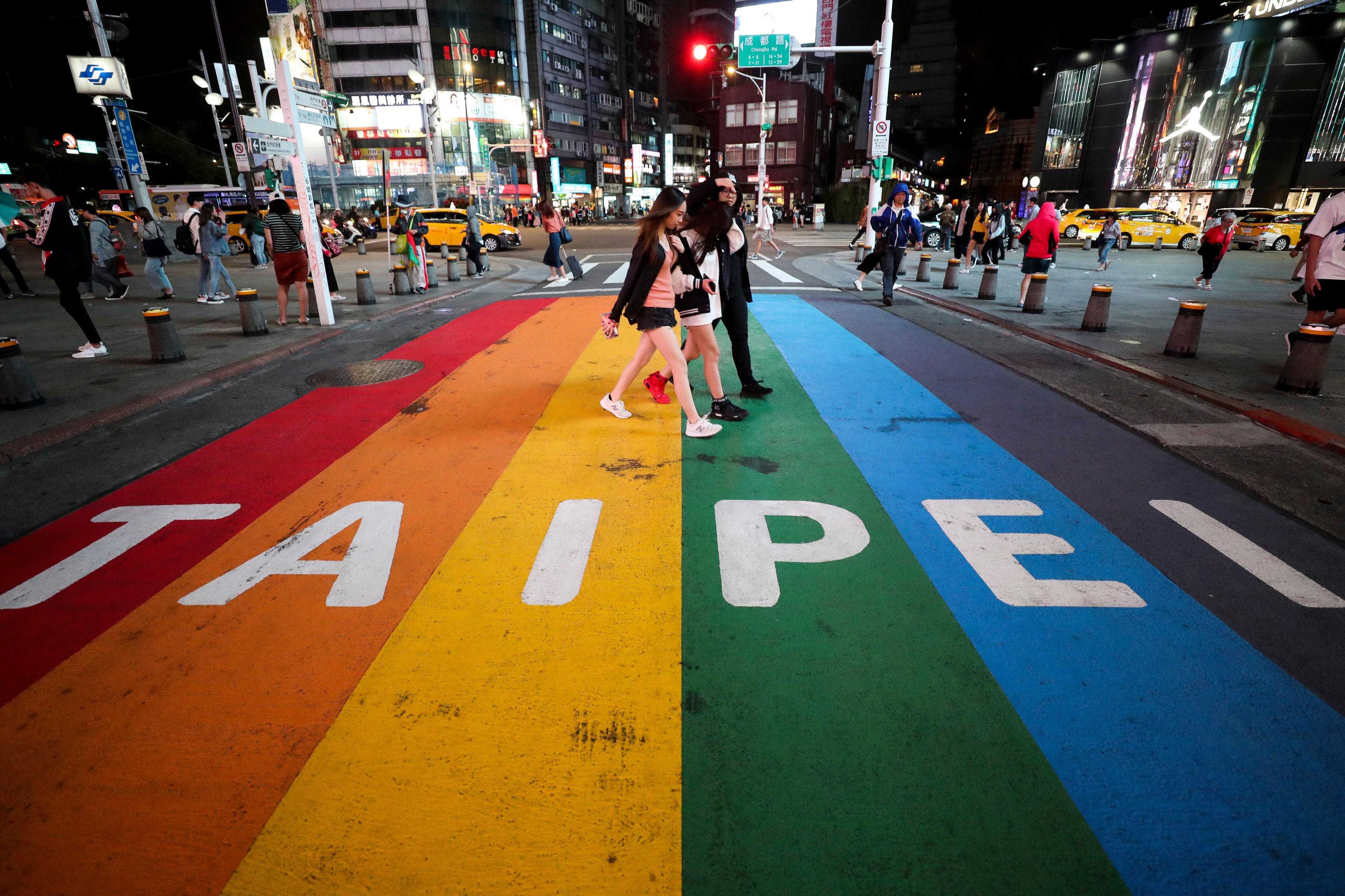 People walk across a pedestrian lane painted in the colours of the rainbow flag in Taipei on October 14, 2019. The government has earned praise for liberal policies like gay marriage, but seems much less enthusiastic about tackling serious issues such as crime. Photo: EPA-EFE