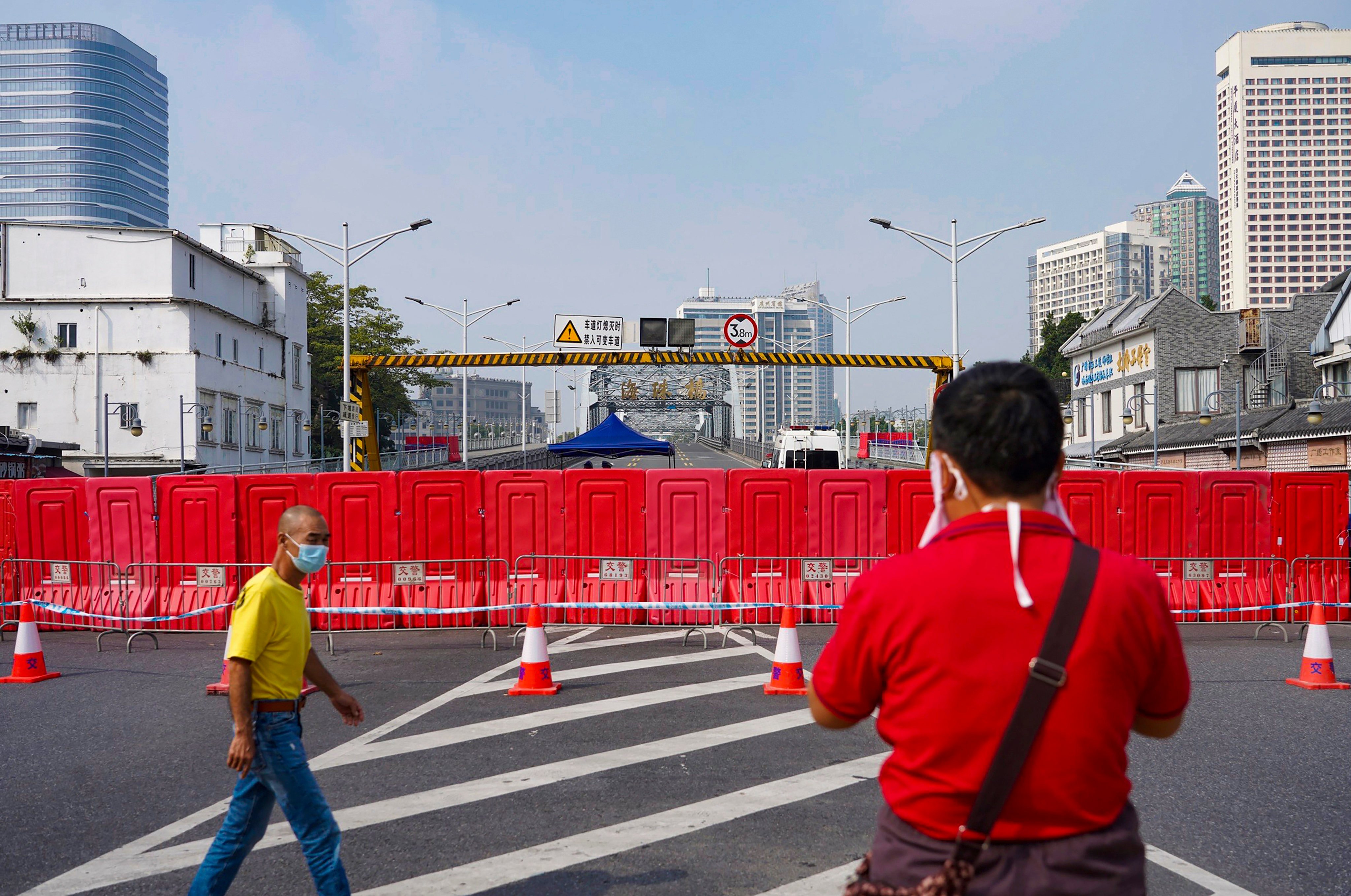Residents wearing masks pass by barriers used to form a security checkpoint in Haizhu district in Guangzhou on Friday. Photo: AP