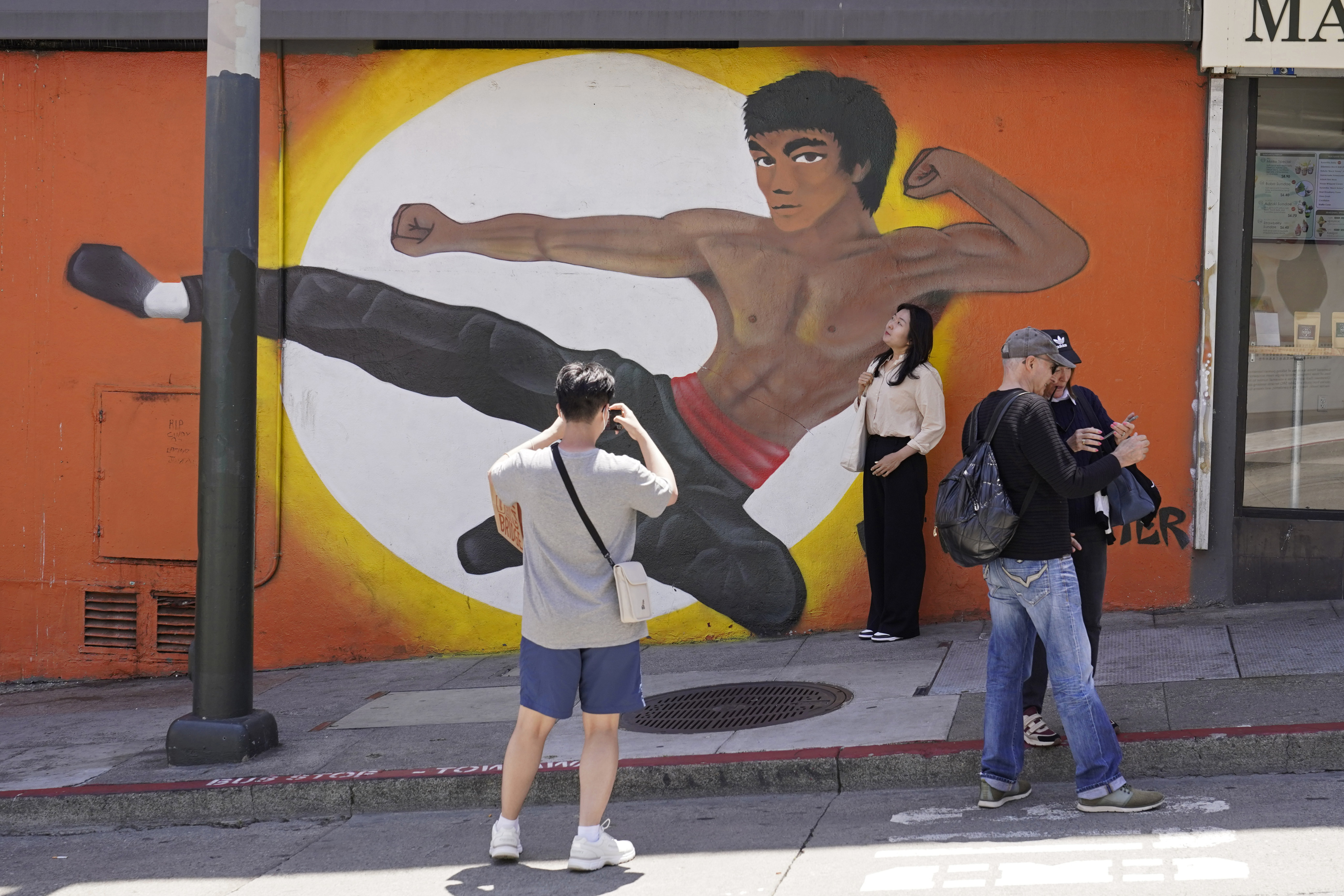 People stop to take pictures by a Chinatown mural of martial artist Bruce Lee in San Francisco on May 23. Lee is a household name in kung fu films, and not the only Hongkonger to have made their mark on the global stage. Photo: AP