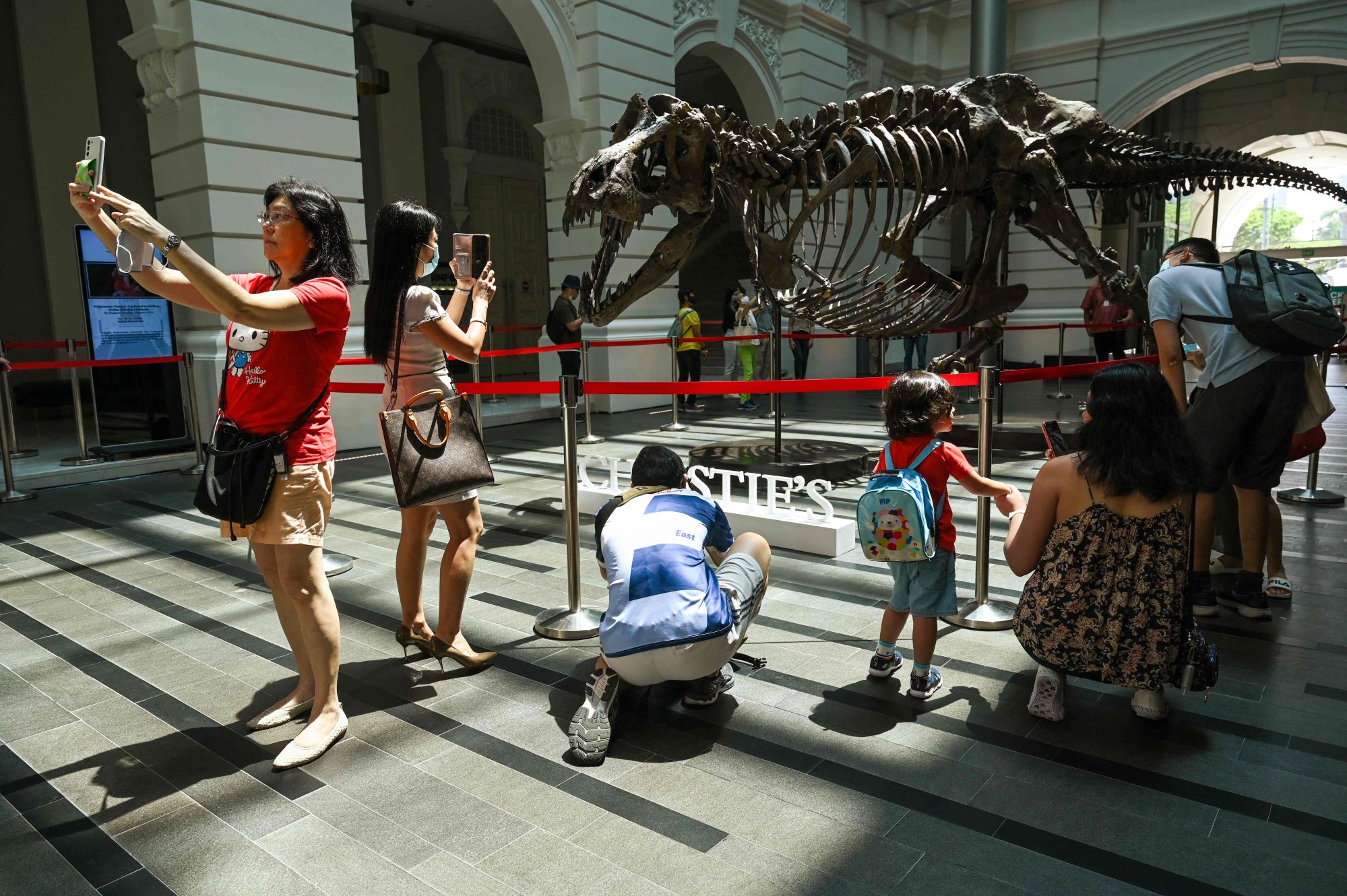 Visitors use their mobile phones to take selfies with the dinosaur skeleton in Singapore. Photo: AFP