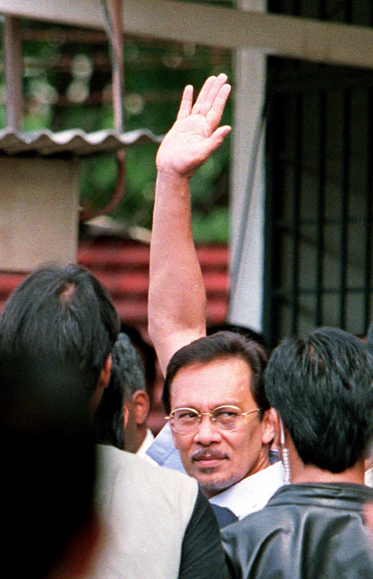 Anwar Ibrahim waves to supporters in Kuala Lumpur as he is led into court to be charged on September 30, 1998. File photo: AP