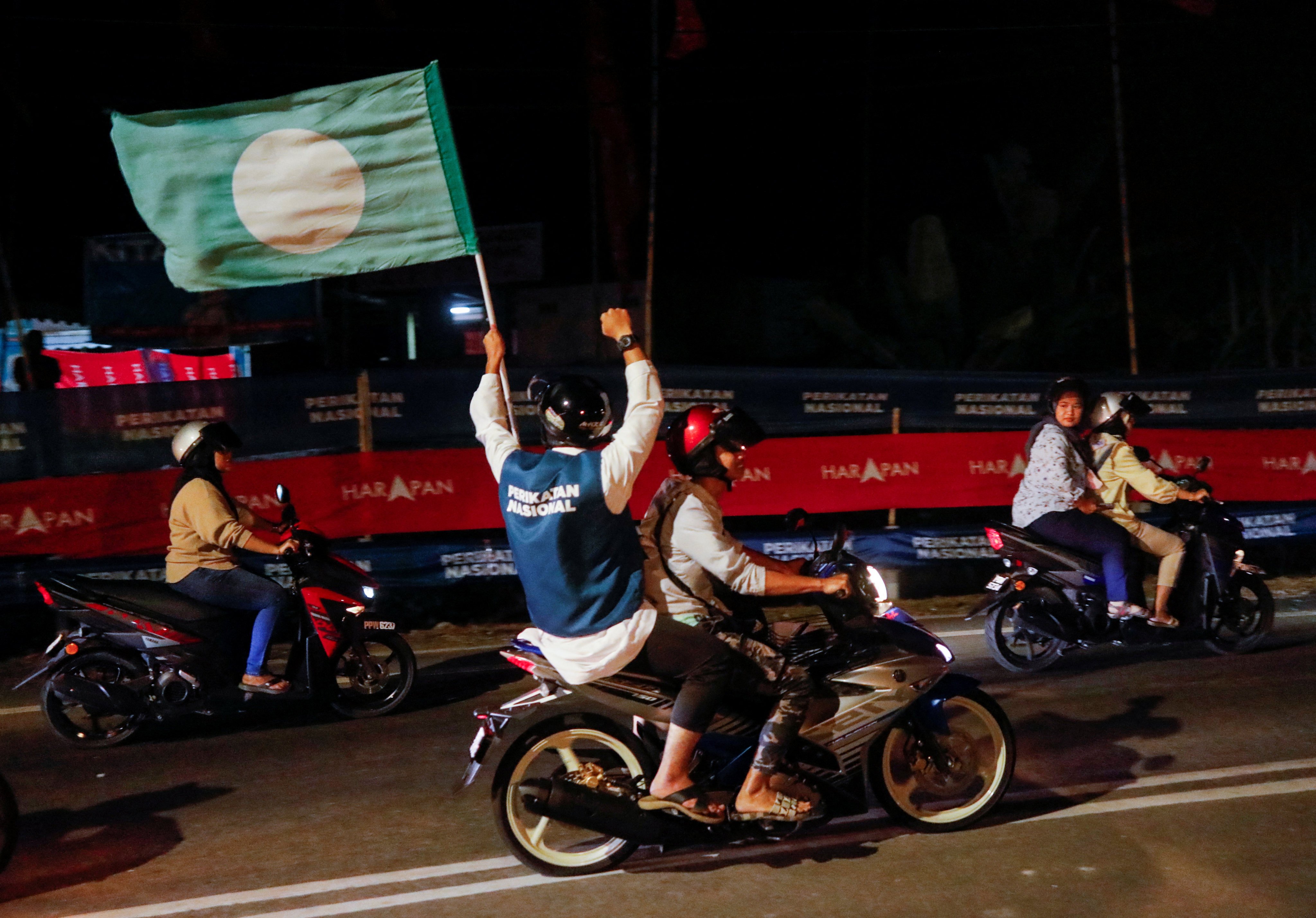 A pillion waves a PAS flag in Penang, Malaysia, on November 18, 2022. Photo: Reuters
