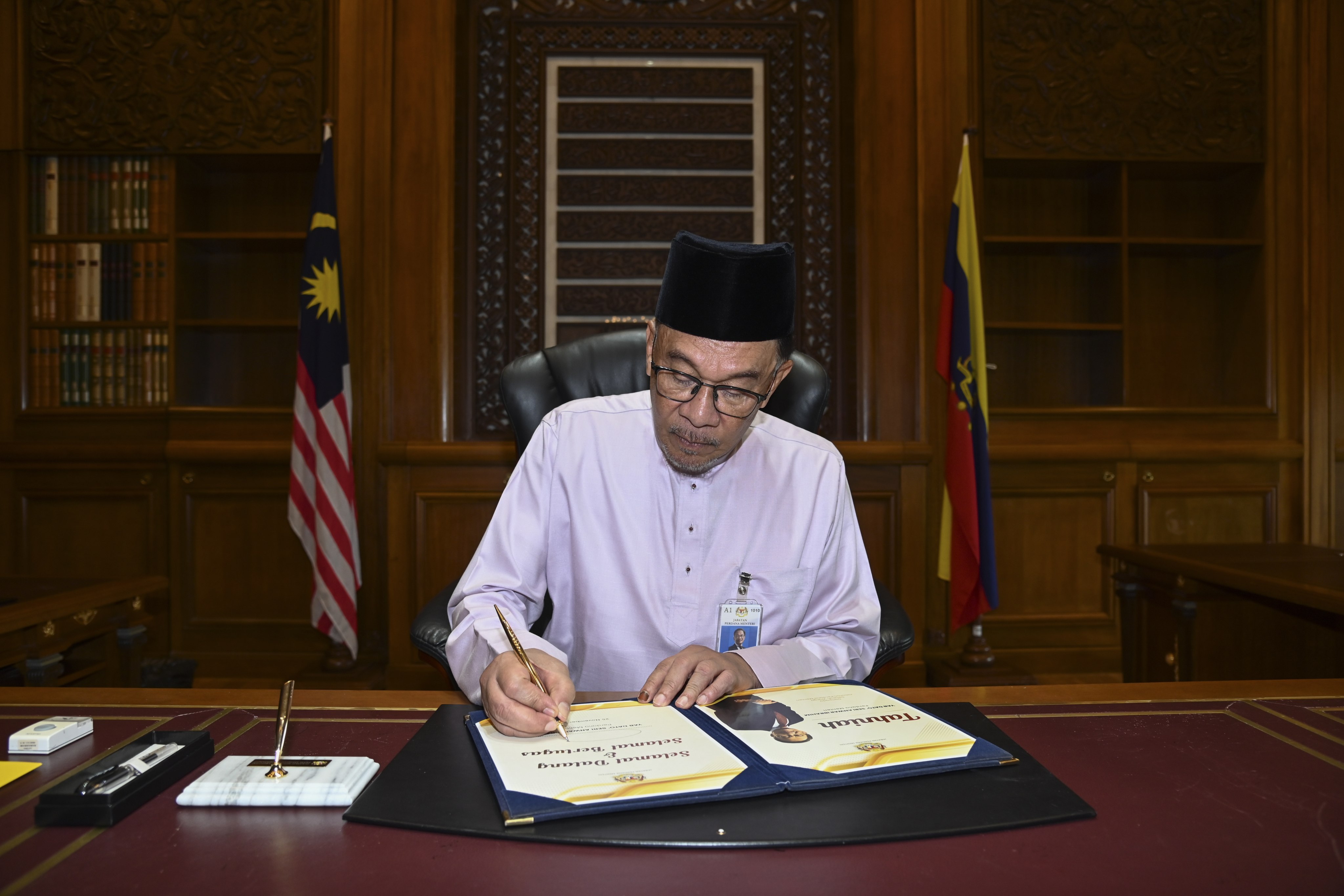 Malaysia’s new Prime Minister Anwar Ibrahim signing documents on his first day at the Prime Minister’s Office in Putrajaya. Photo: Malaysia Information Ministry/EPA-EFE