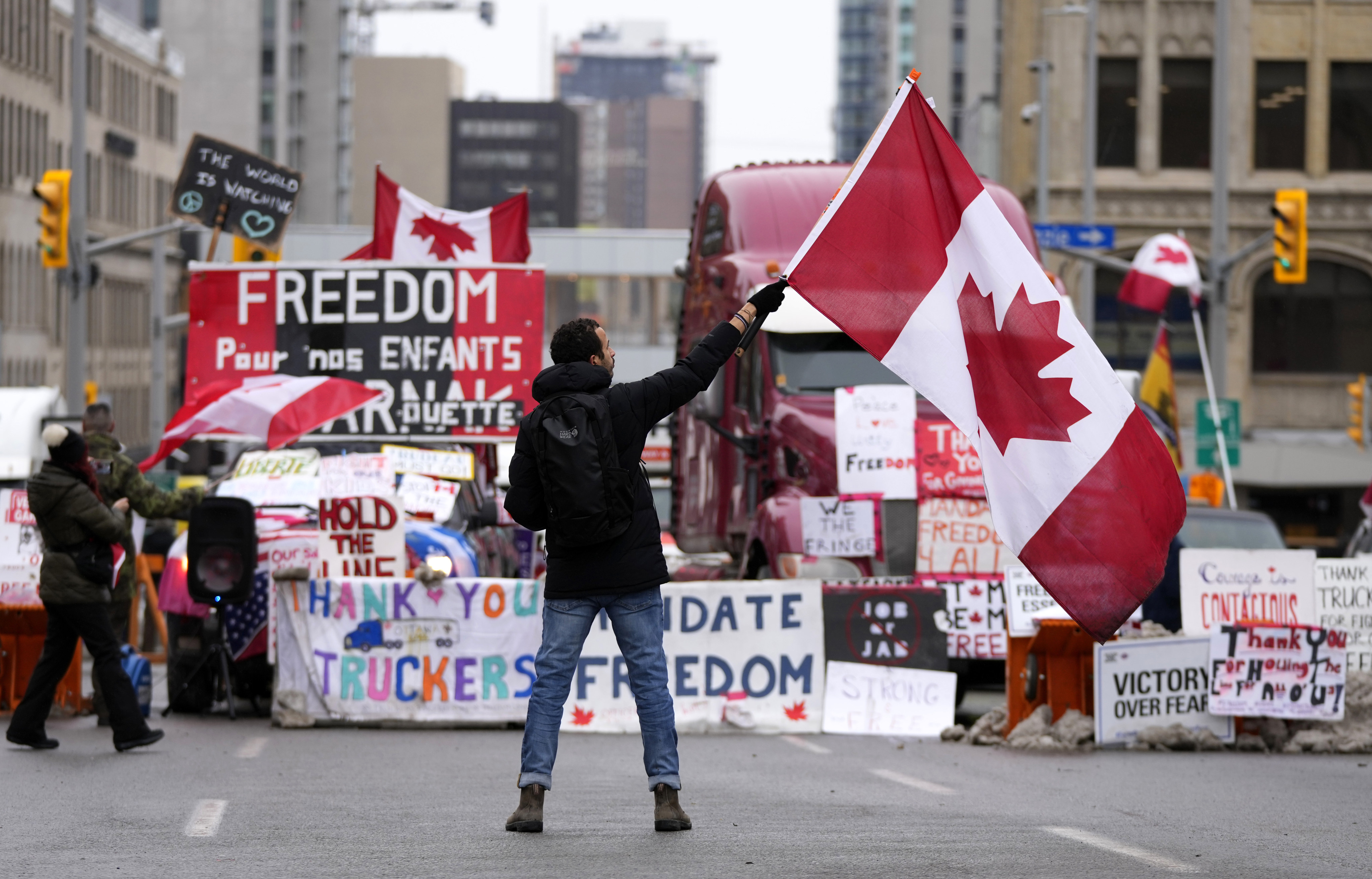 A protester waves a Canadian flag in front of parked vehicles in Ottawa in February. Photo: The Canadian Press via AP