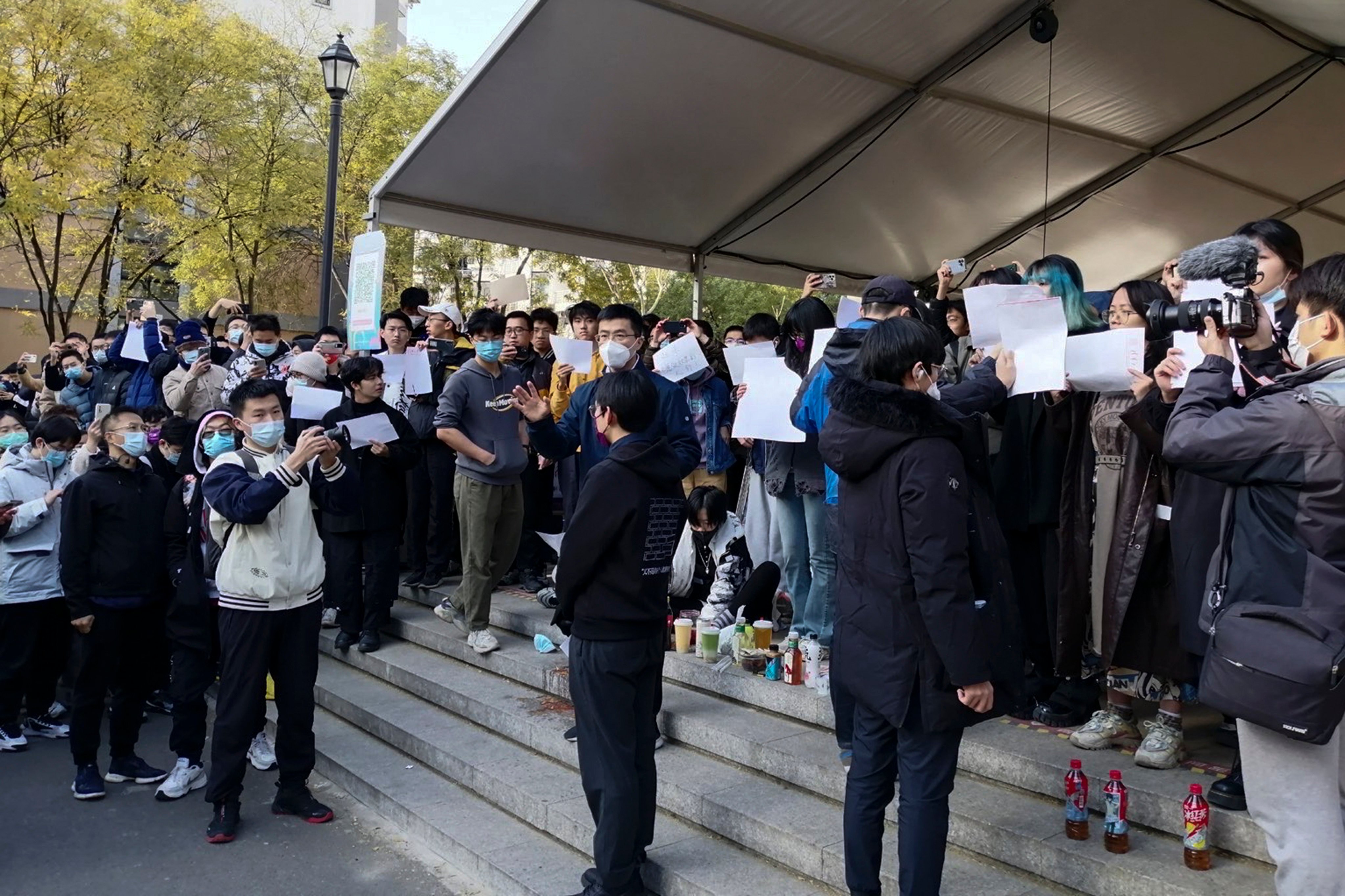 Students hold up blank papers as they stage a protest at Tsinghua University in Beijing on Sunday. Photo: AP
