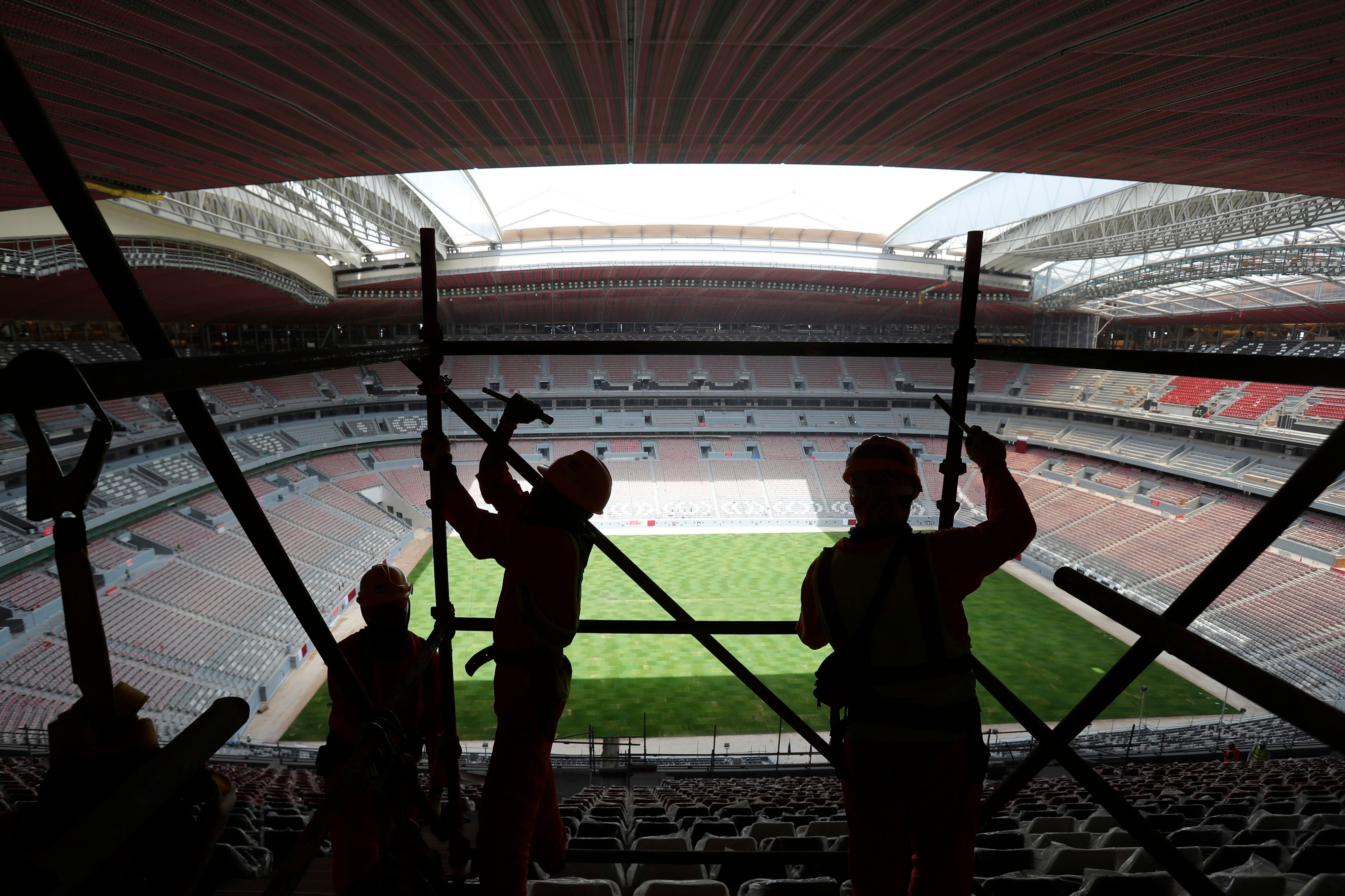 Labourers remove scaffolding at the Al Bayt stadium in Al Khor, Qatar. Migrant labourers who built Qatar’s World Cup stadiums often worked long hours under harsh conditions and were subjected to discrimination, wage theft and other abuses as their employers evaded accountability. Photo: AP