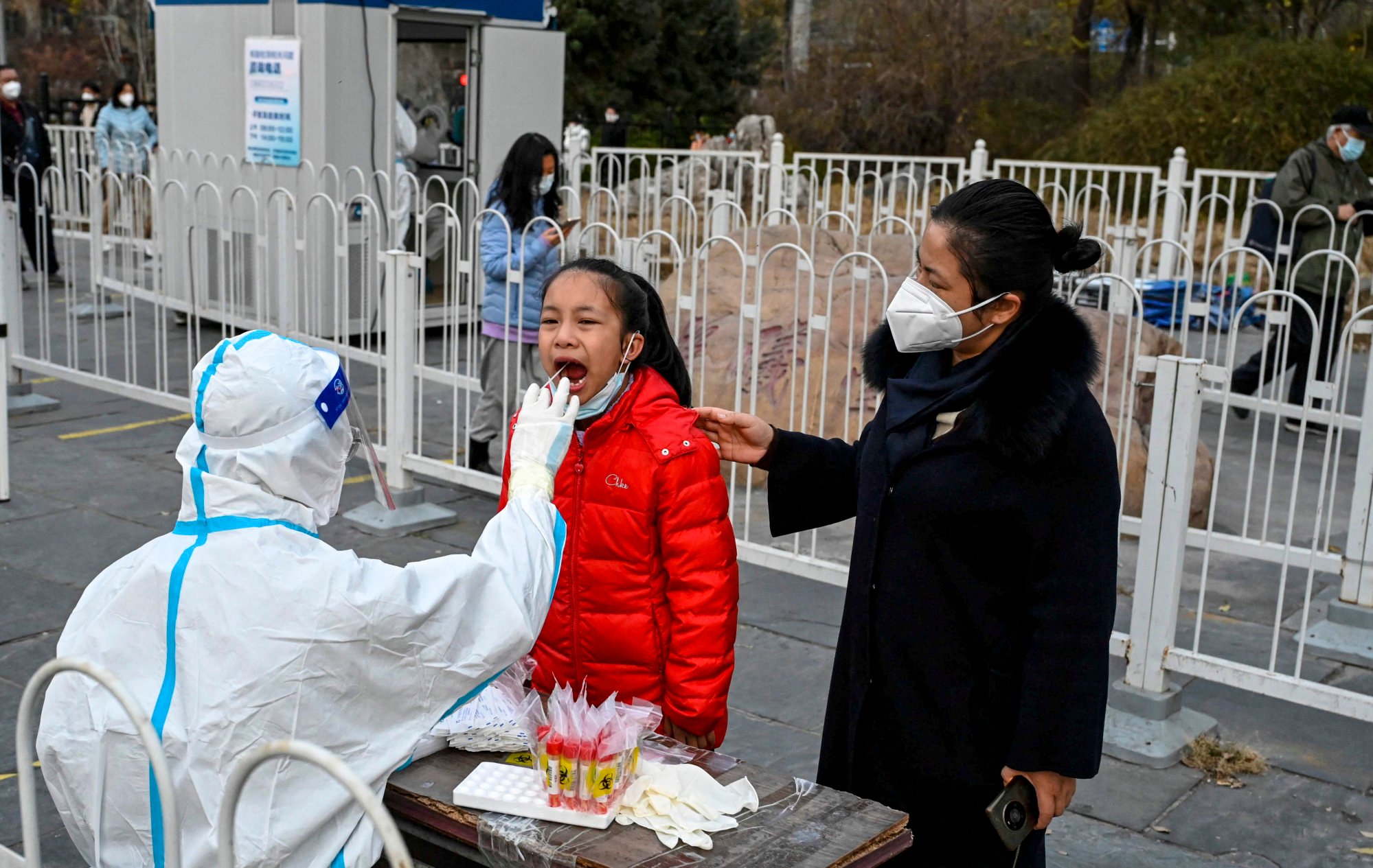 A health worker at a collection station in Beijing takes a swab sample from a girl. Photo: AFP