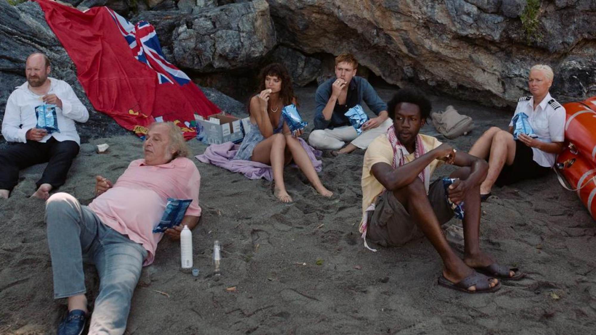 Wealthy cruise passengers, and crew, marooned on an island, in a still from Triangle of Sadness.