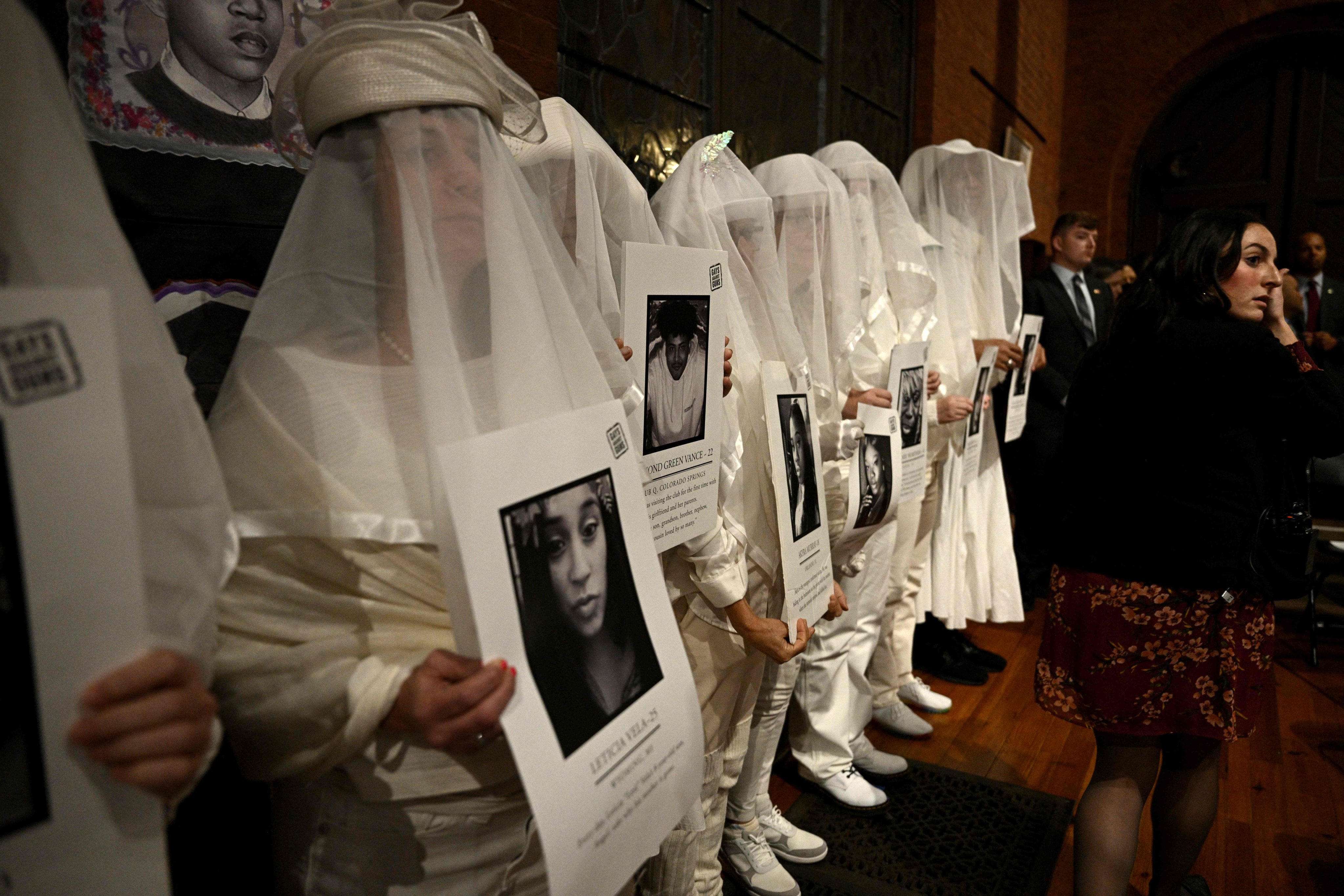 Attendees hold images of victims of gun violence at a vigil on Wednesday. Photo: AFP