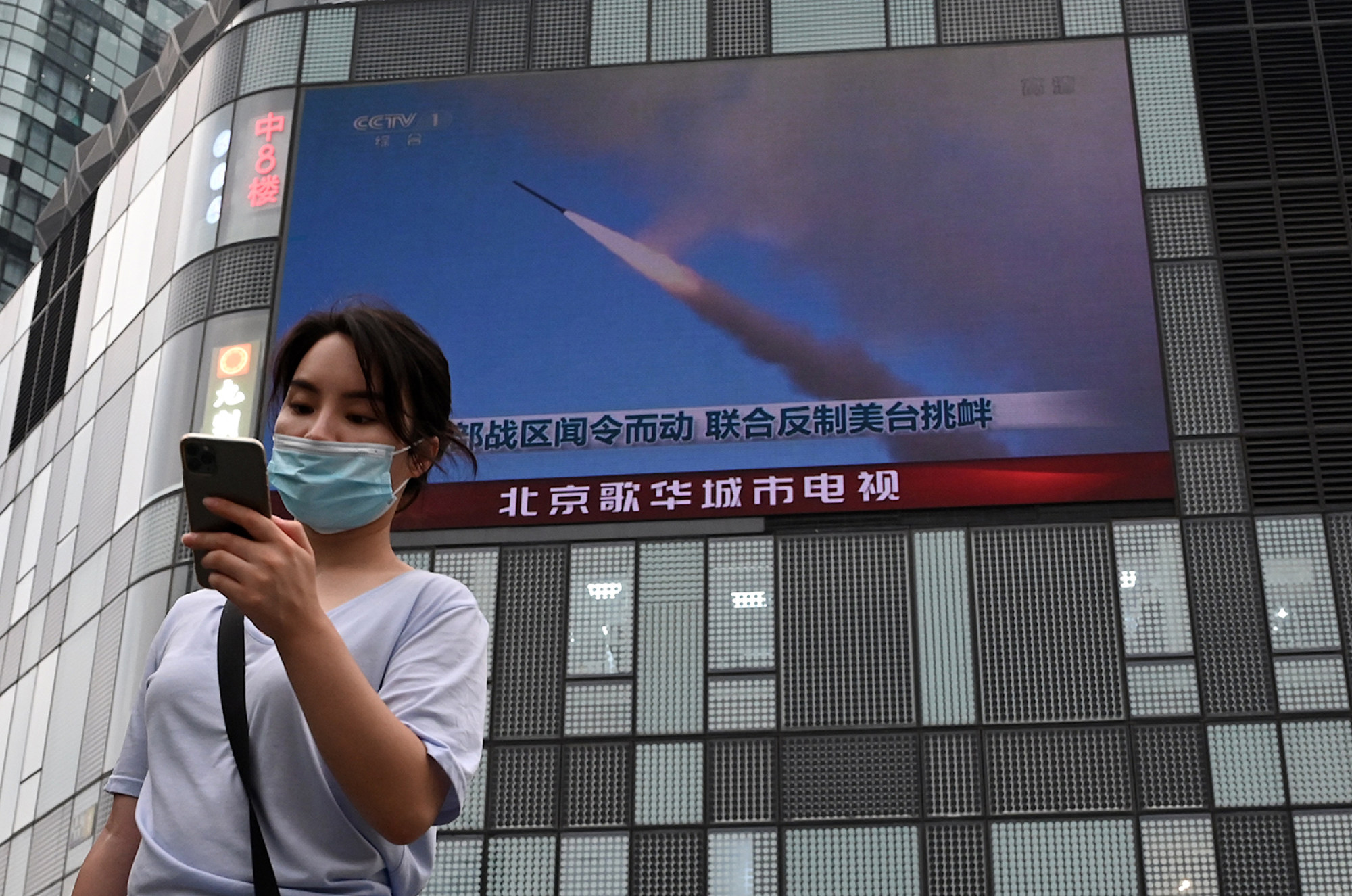 A woman in Beijing walks past a large screen showing a news broadcast about China’s military exercises encircling Taiwan in August. Photo: Getty Images/TNS via AFP