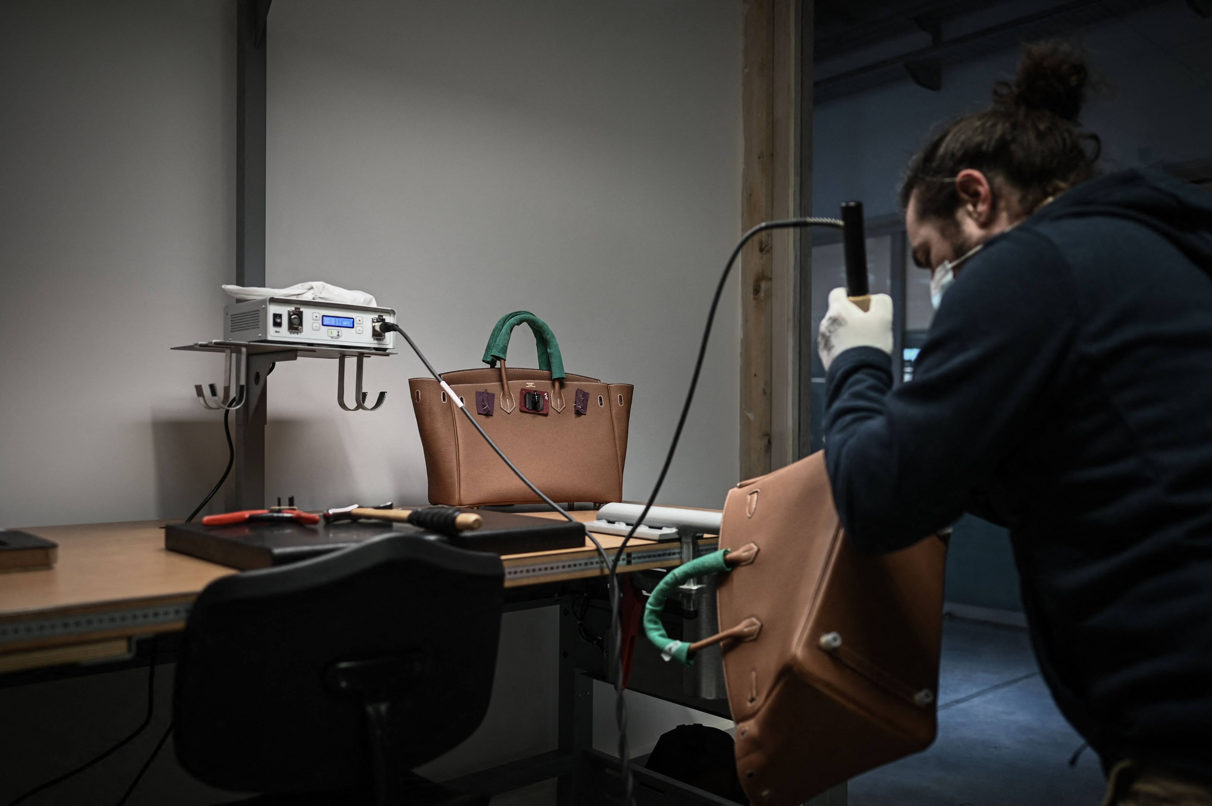 An employee working on a handbag at an Hermès leather goods workshop. The luxury goods manufacturer was the first to offer a restoration service. Photo: AFP