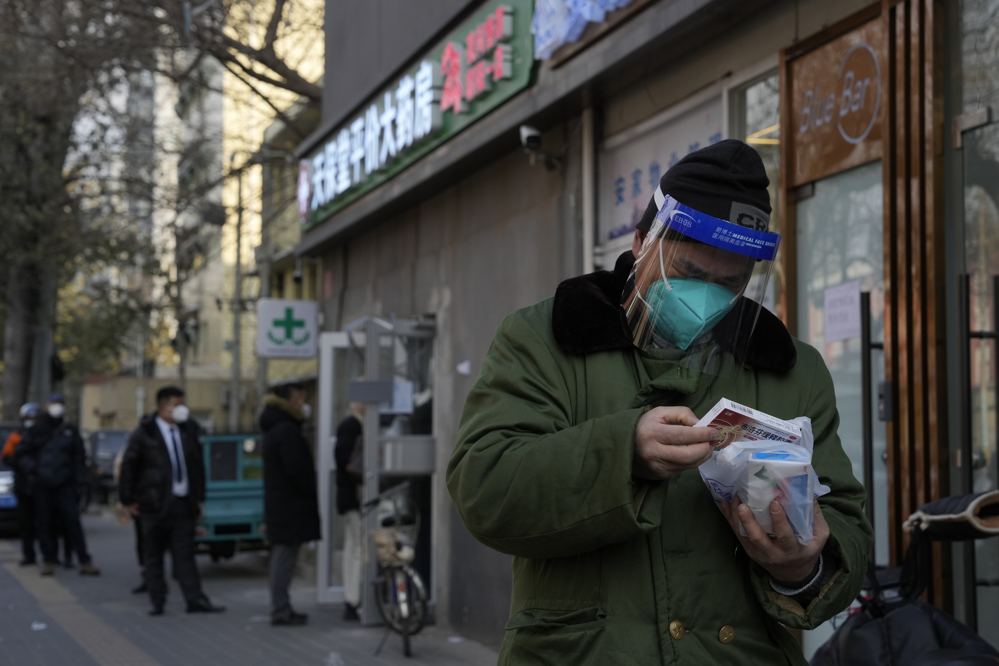 A man checks his medicine bought from a pharmacy as a queue forms outside in Beijing as China began implementing a more relaxed version of its strict ‘zero-COVID’ policy. Photo: AP