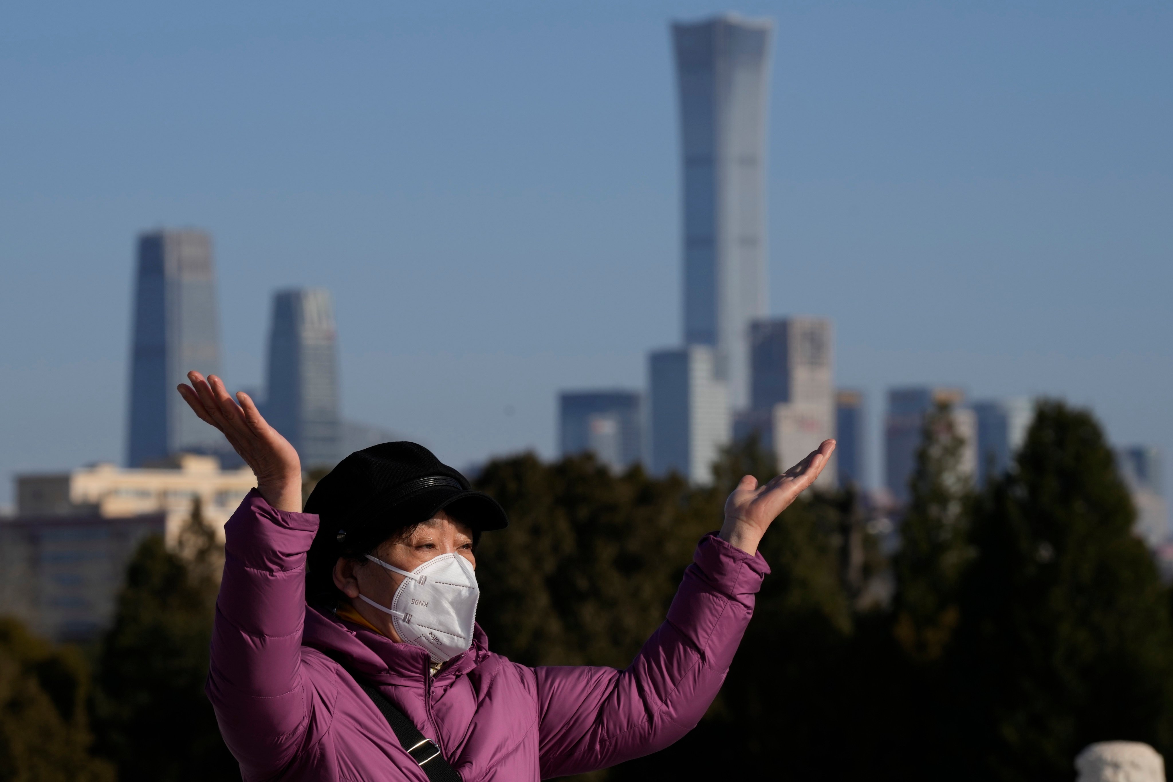 A woman poses for a photo in the Temple of Heaven Park, in Beijing, with the city skyline in the background, on December 8. Photo: AP