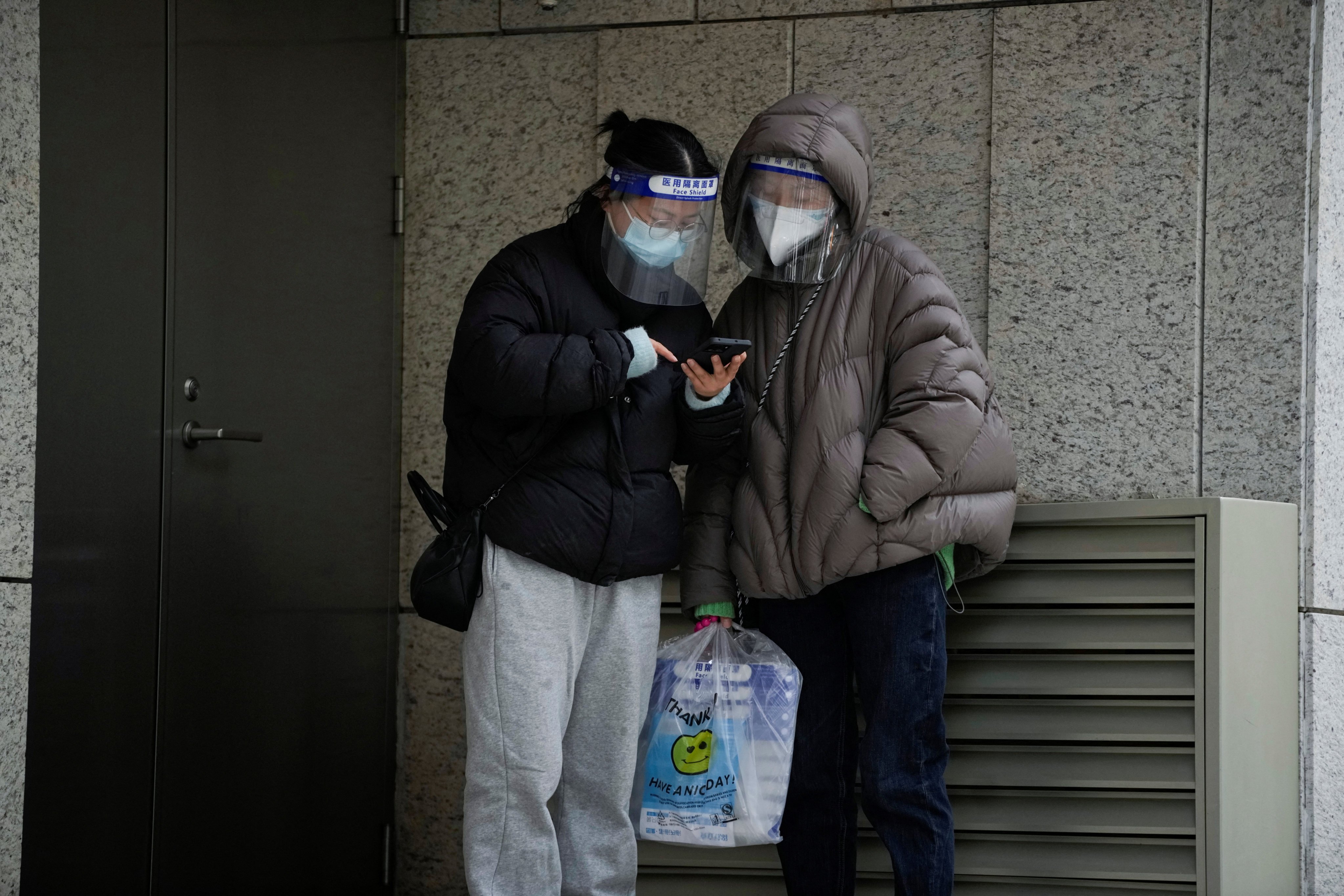 Women wearing face masks and face shields check a phone on a street, as Covid-19 outbreaks continue in Shanghai on December 12. Photo: Reuters