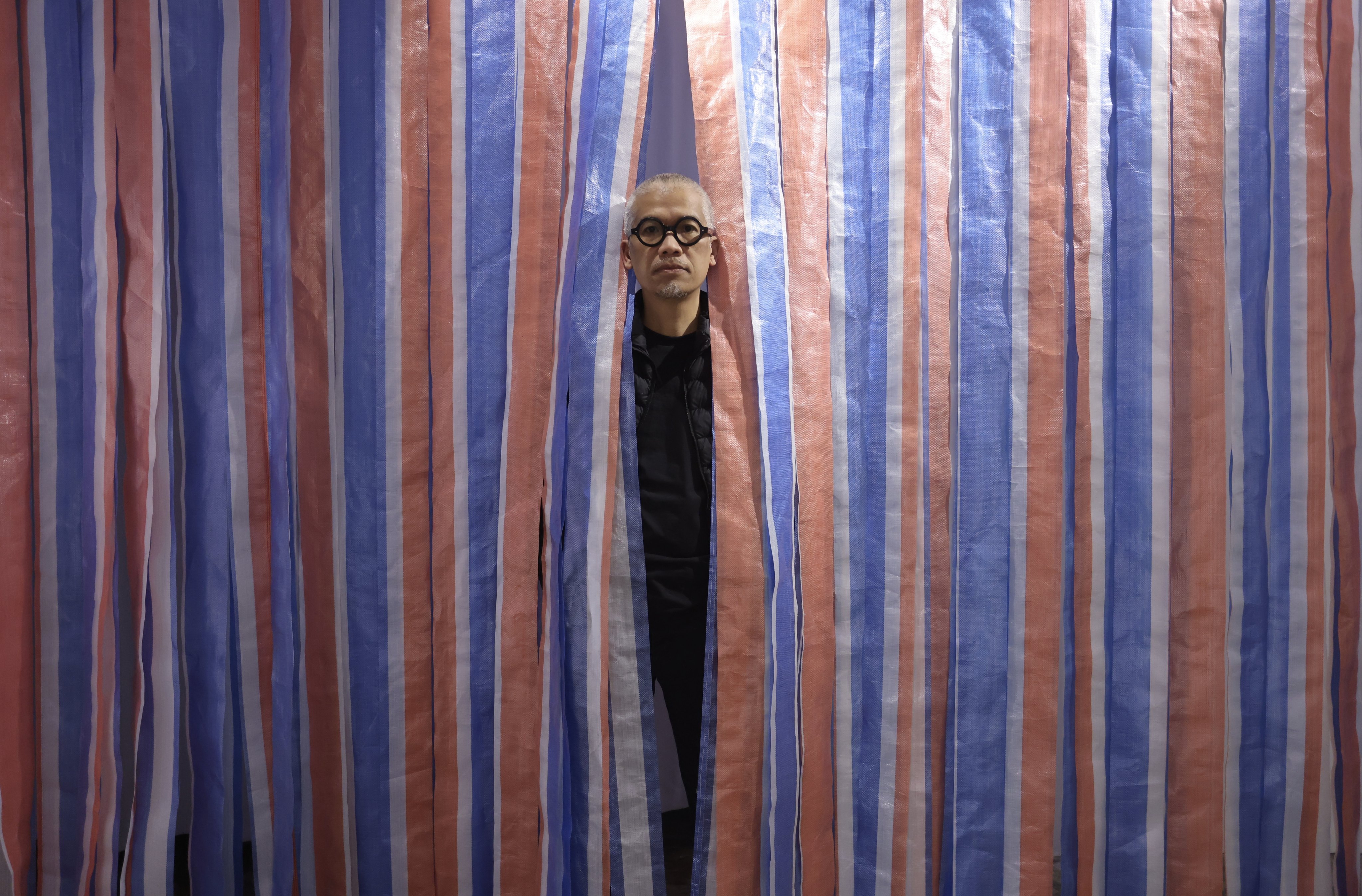 Stanley Wong Ping-pui at his exhibition ‘on hong kong // anothermountainman solo 2022’ at Lucie Chang Fine Arts in Wong Chuk Hang. The artist also known as anothermountainman has long taken inspiration from the red, white and blue canvas material widely used in Hong Kong. Photo: Jonathan Wong