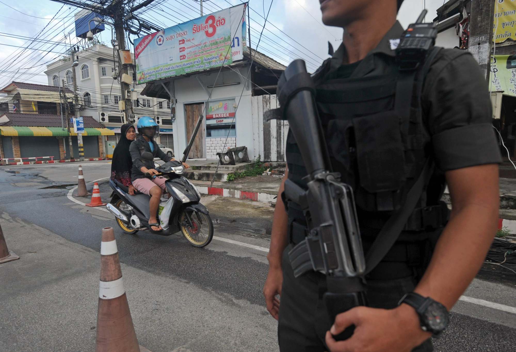 Thai Muslim women ride a motorcycle past a police officer at a market in Thailand’s restive southern province of Narathiwat. Photo: AFP