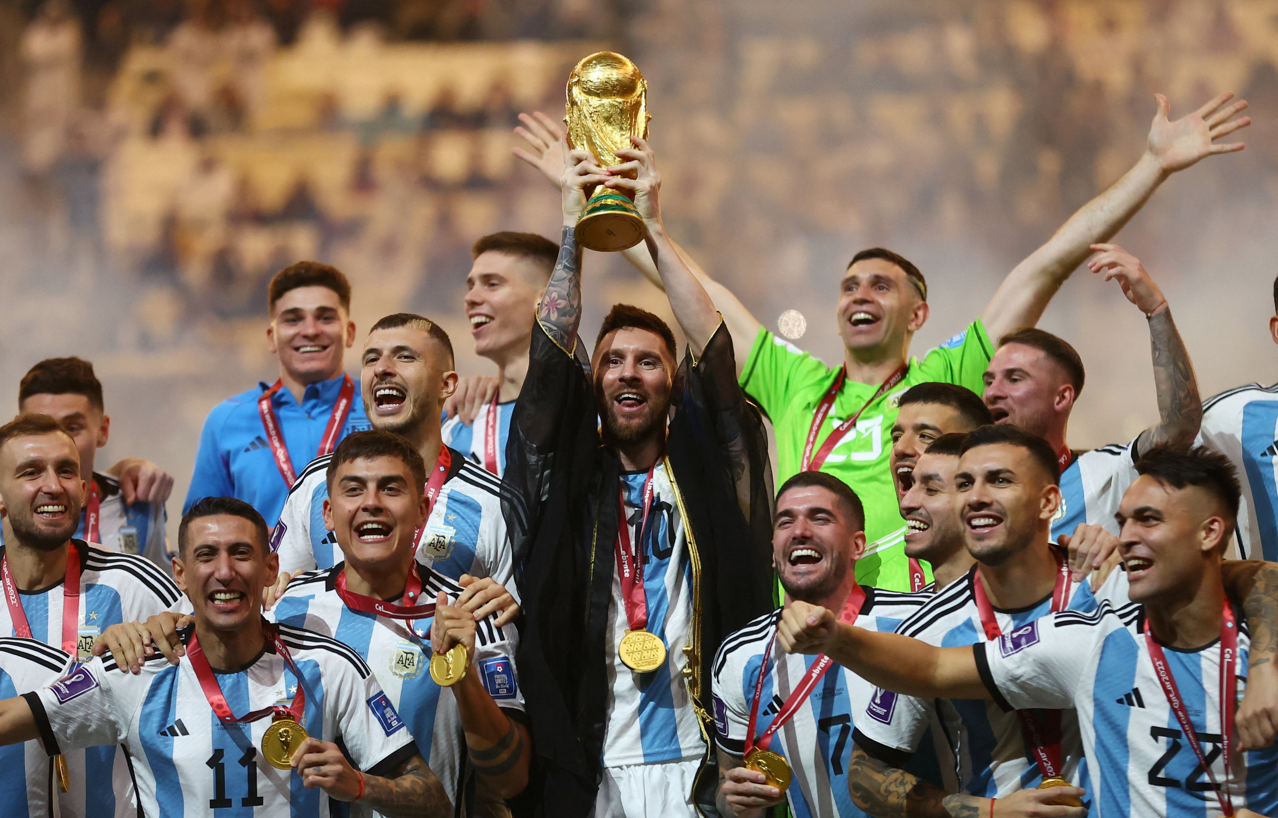 Lionel Messi lifts the World Cup trophy alongside teammates as they celebrate their victory. Photo: Reuters