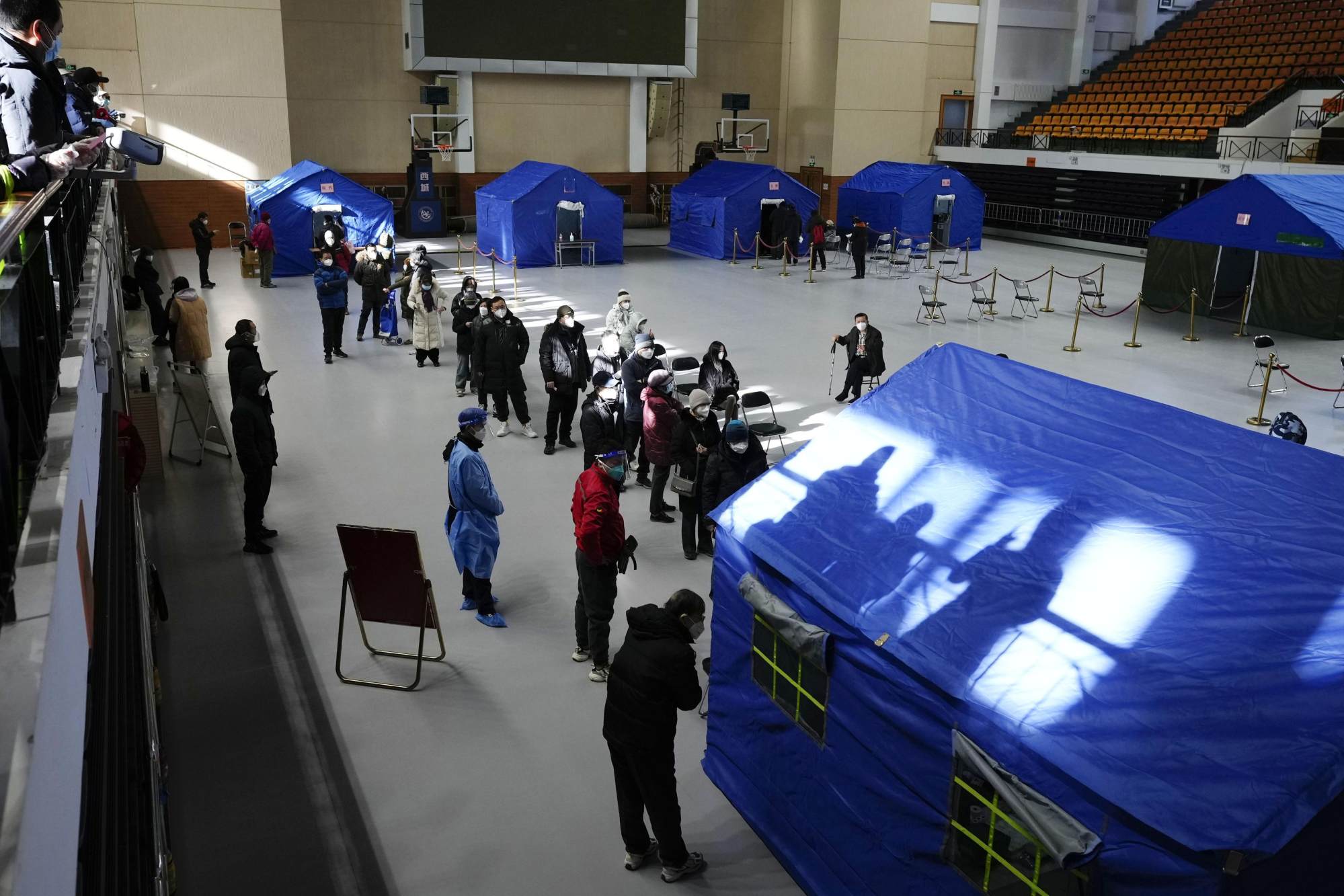 People line up for fever outpatient services at a makeshift clinic in a Beijing gym. Photo: Kyodo