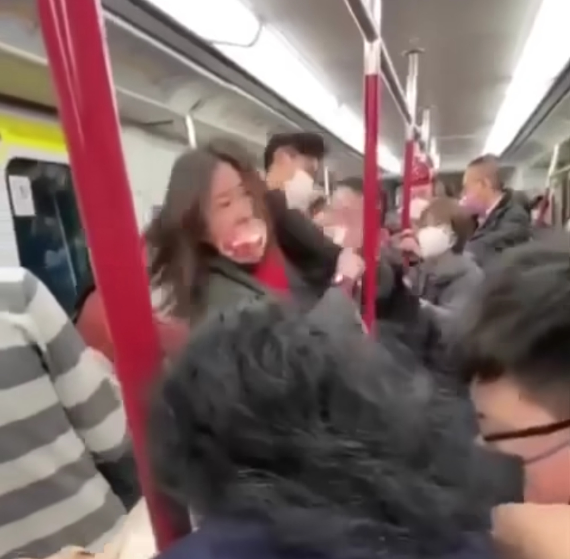 The man and woman, in pink mask, trade blows in a fast-moving Hong Kong mass transit railway carriage.