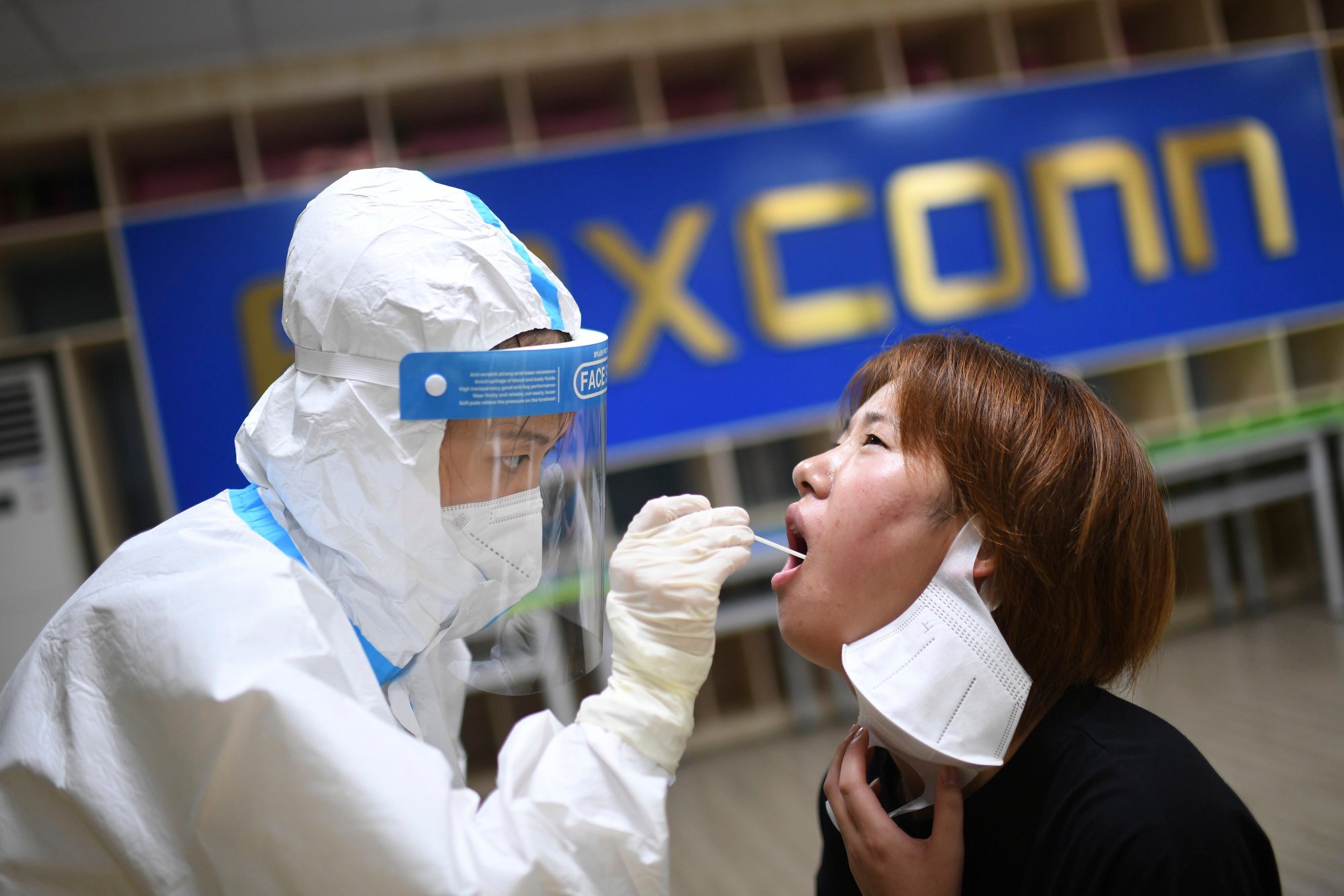 A medical worker takes a swab sample to test for Covid-19 from a worker at Foxconn Technology Group’s manufacturing complex in Wuhan, where a coronavirus outbreak has disrupted production. Photo: AP