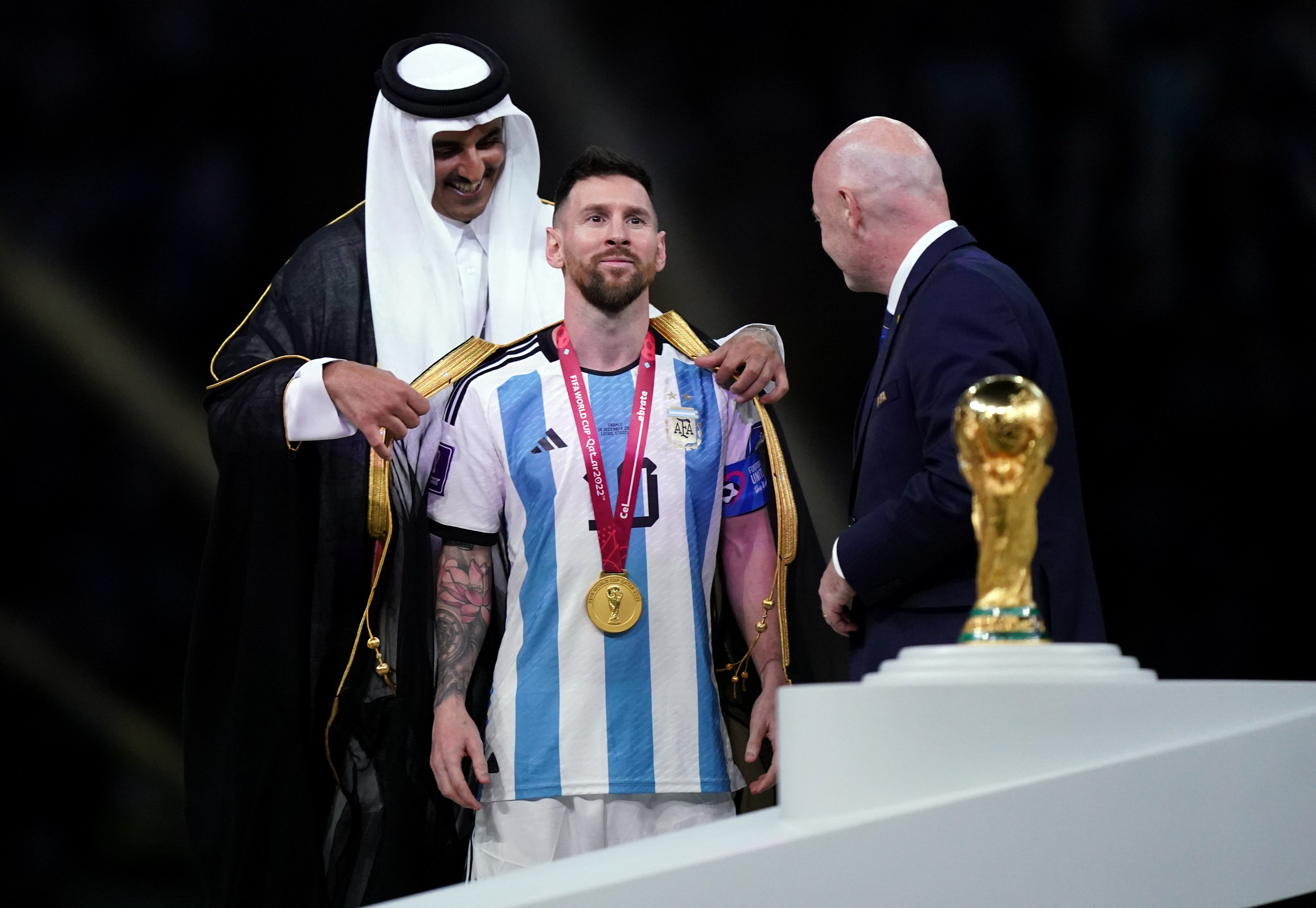 Qatar emir Sheikh Tamim bin Hamad Al Thani covers Argentina’s Lionel Messi in an Arab bisht as Fifa president Gianni Infantino waits to present the winning trophy at Lusail Stadium on December 18. Photo: PA Wire/dpa