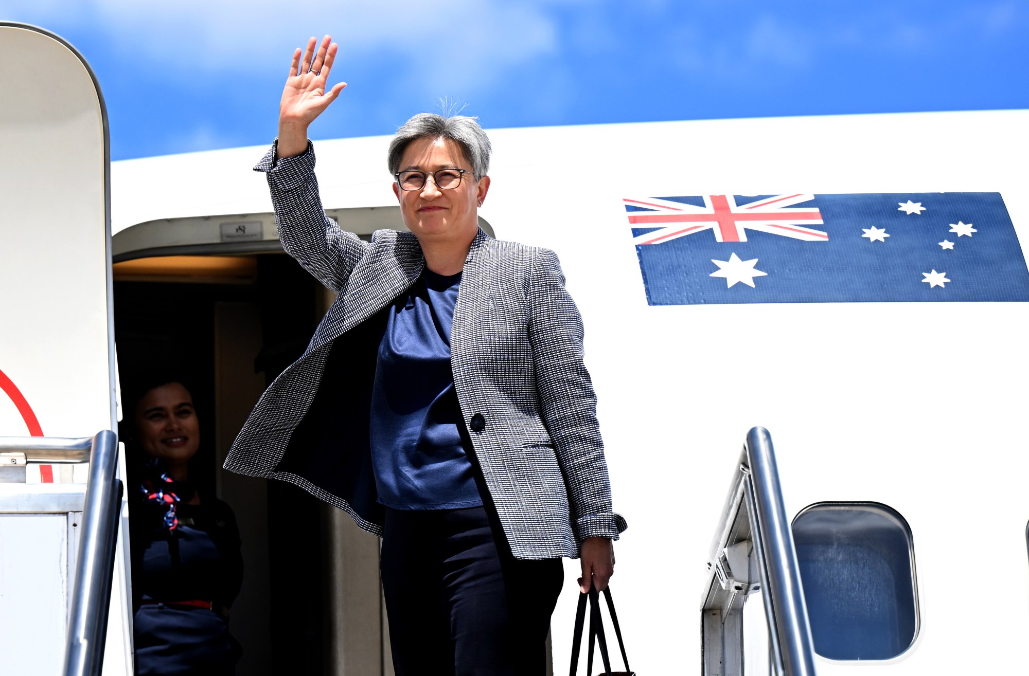 Foreign Minister Penny Wong waves before boarding a plane in Canberra on Tuesday to travel to China to meet with Foreign Affairs Minister Wang Yi. Photo: EPA-EFE