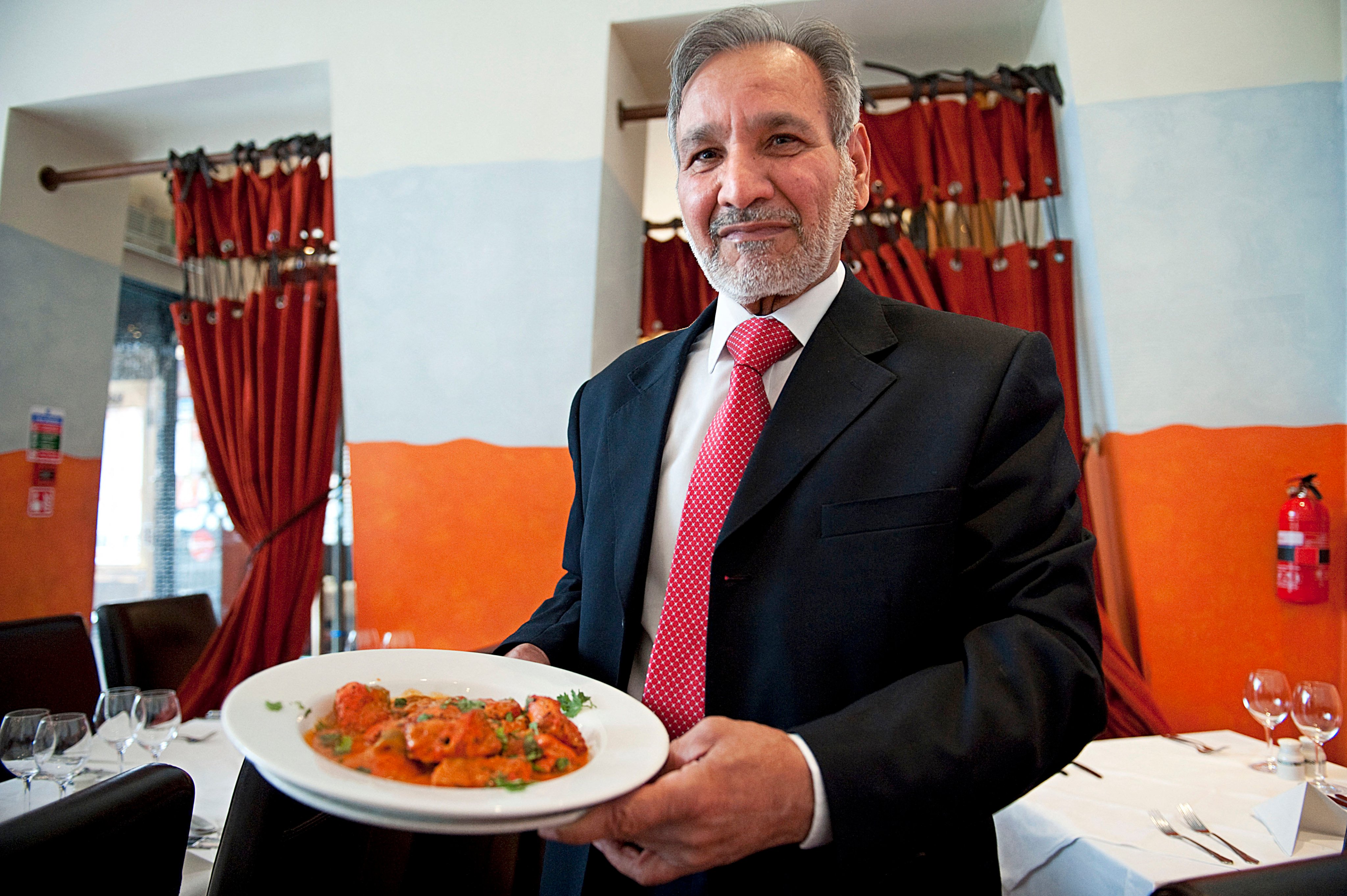 Ahmed Aslam Ali, the owner of the Shish Mahal restaurant in Glasgow, holds a plate of chicken tikka masala in his Shish Mahal restaurant in Glasgow, where he claims to have come up with the dish in the 1970s. Photo: AFP
