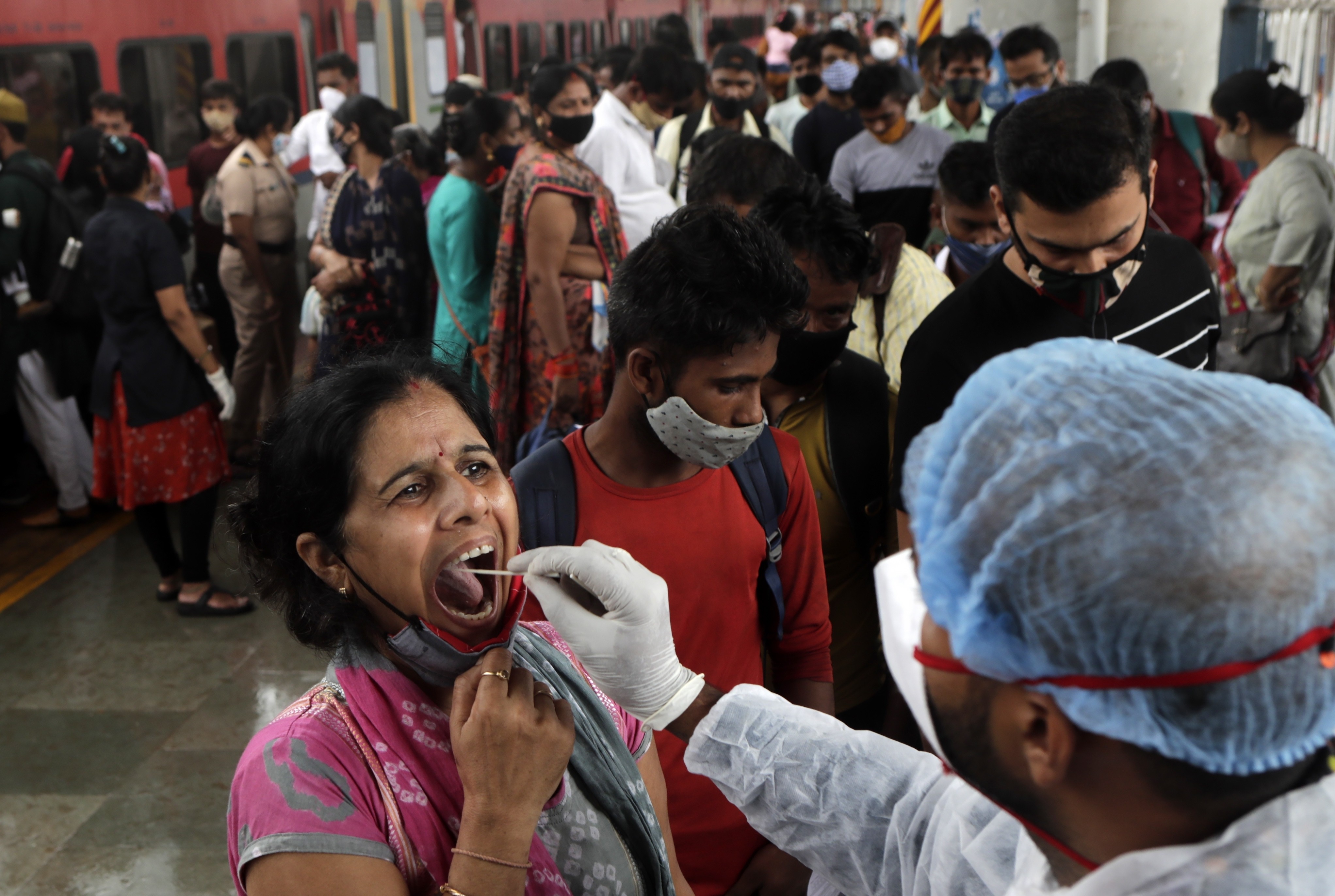A health worker collects a swab sample from a traveler to test for Covid-19 at a train station in Mumbai, India. Photo: AP/File