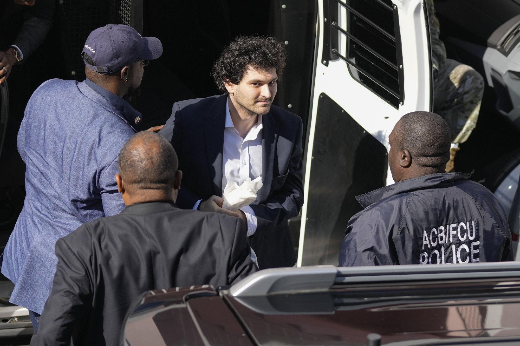 FTX founder Sam Bankman-Fried (center) arrived at the Magistrate Court building for a hearing in Nassau of the Bahamas on Wednesday, Dec. 21, 2022 before his extradition to the United States to face embezzlement charges. Photo: AP