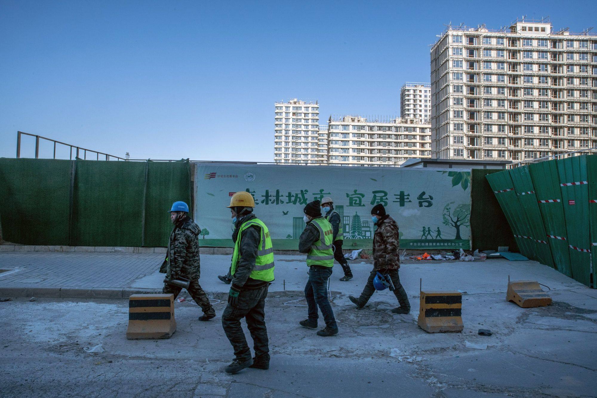 Workers walk past residential buildings under construction in Beijing on December 16.China’s State Council has called for rescue measures for the property sector to be properly implemented. Photo: Bloomberg