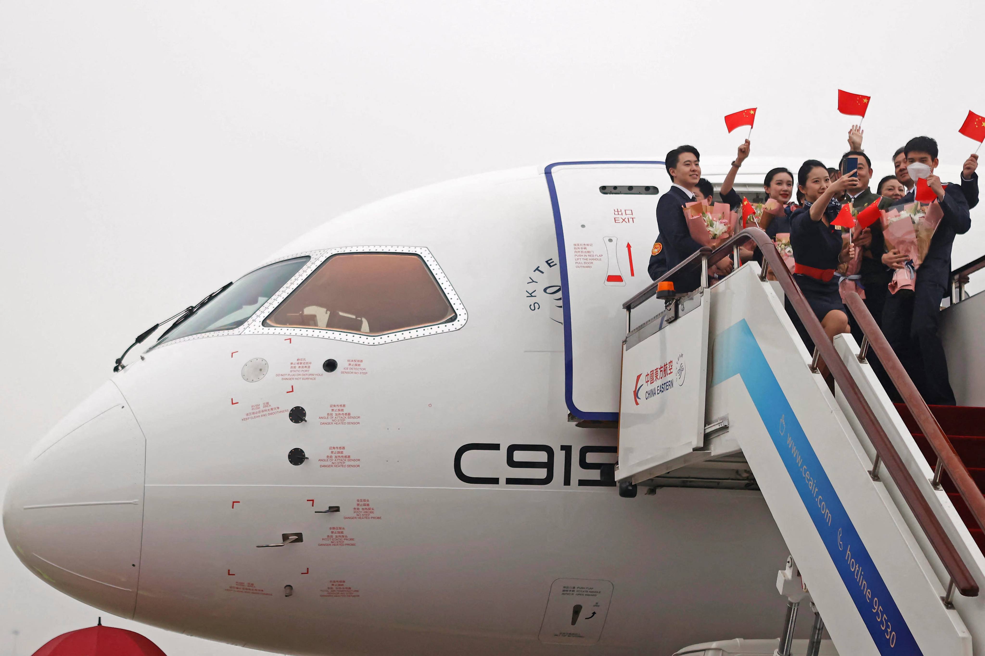 Crew members wave Chinese flags out of a Comac C919 aircraft, China’s first domestically produced large passenger jet, after landing at Hongqiao International Airport  on December 9. Photo: AFP