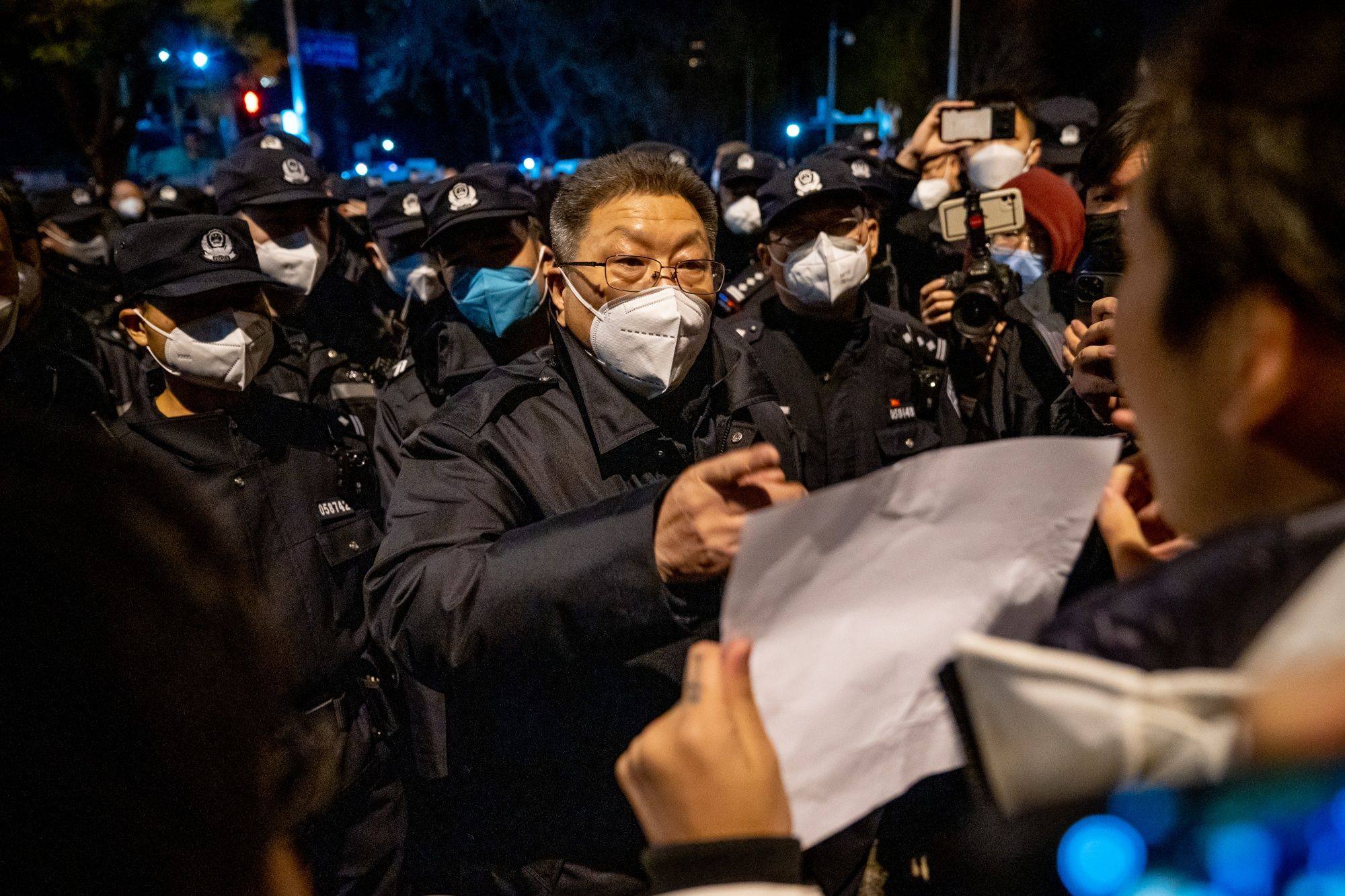A local official shouts at a demonstrator holding a blank sign during a protest in Beijing on November 28. The rare outpouring of public anger over China’s continued lockdowns led to a reversal in the country’s pandemic policies, a decision that will ripple through the domestic, regional and global economies. Photo: Bloomberg
