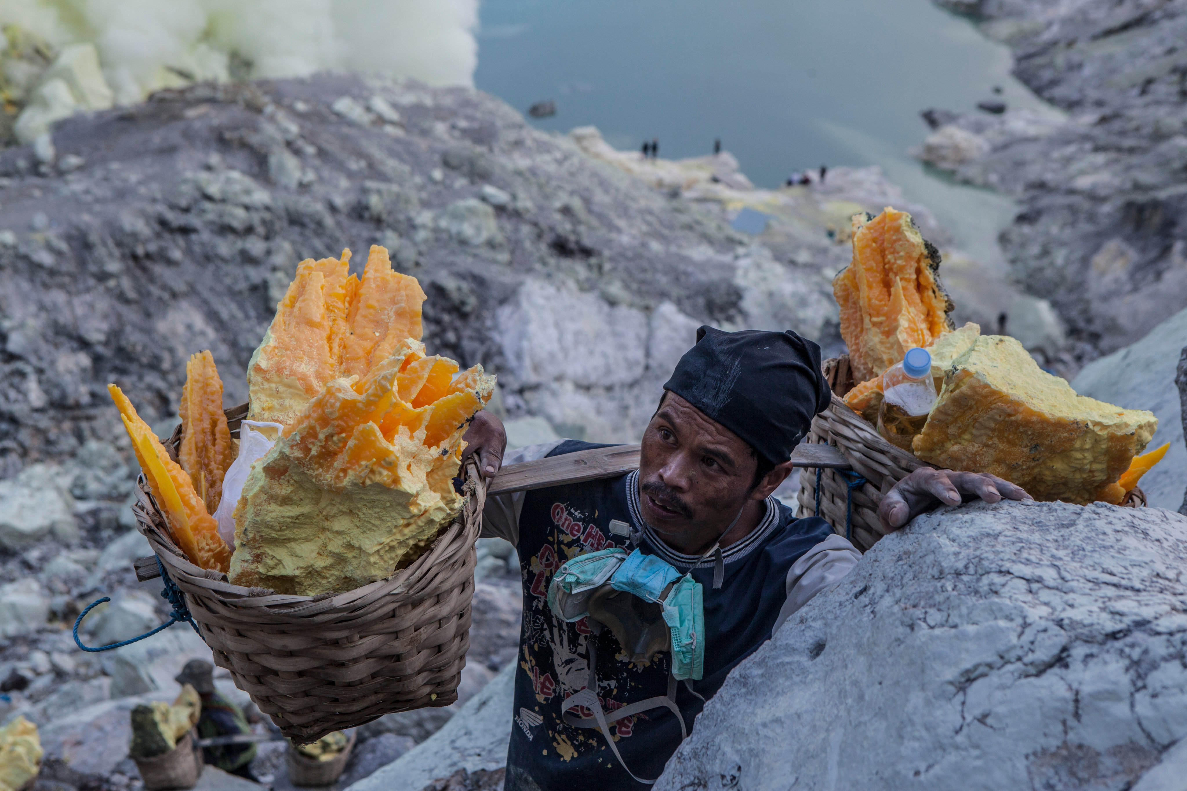 Miner carrying baskets of solid sulphur from the quarry in Indonesia. Photo: Agoes Rudianto/File