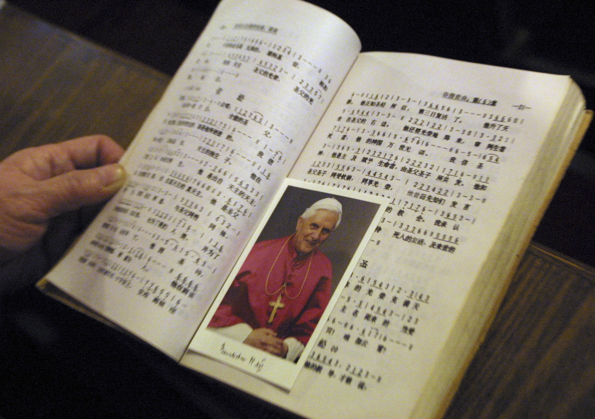 A picture of Pope Benedict XVI between the pages of a hymn book during Mass at a church in Beijing on Christmas Day in 2005. As soon as he was elected, Benedict made clear he wanted to re-establish diplomatic relations with China that were severed in 1951. The Vatican announced on December 31, 2022 that Benedict had died at age 95. Photo: AP 