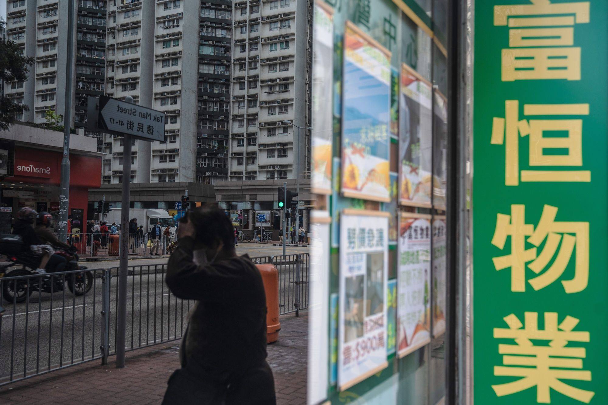 A pedestrian walks past a property agency in Hong Kong on December 5 last year. Residential property in Hong Kong is expected to see a surge in interest this year as sentiment improves and the prospect of reopening the mainland border draws nearer. Photo: Bloomberg