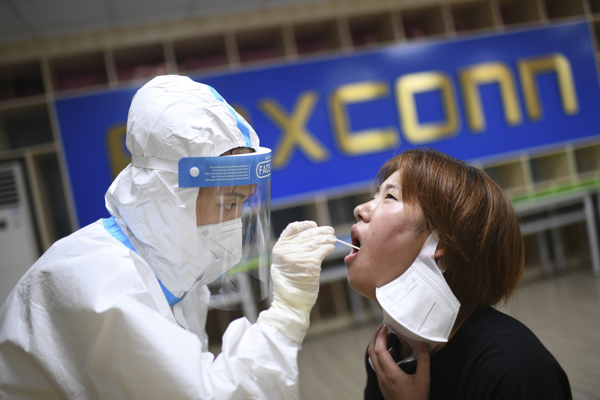 A medical worker takes a Covid swab sample from a worker at a factory run by Apple supplier Foxconn in Wuhan in 2021. Apple AirPods and other iPhone add-ons are now also made in Vietnam. Photo: Chinatopix via AP