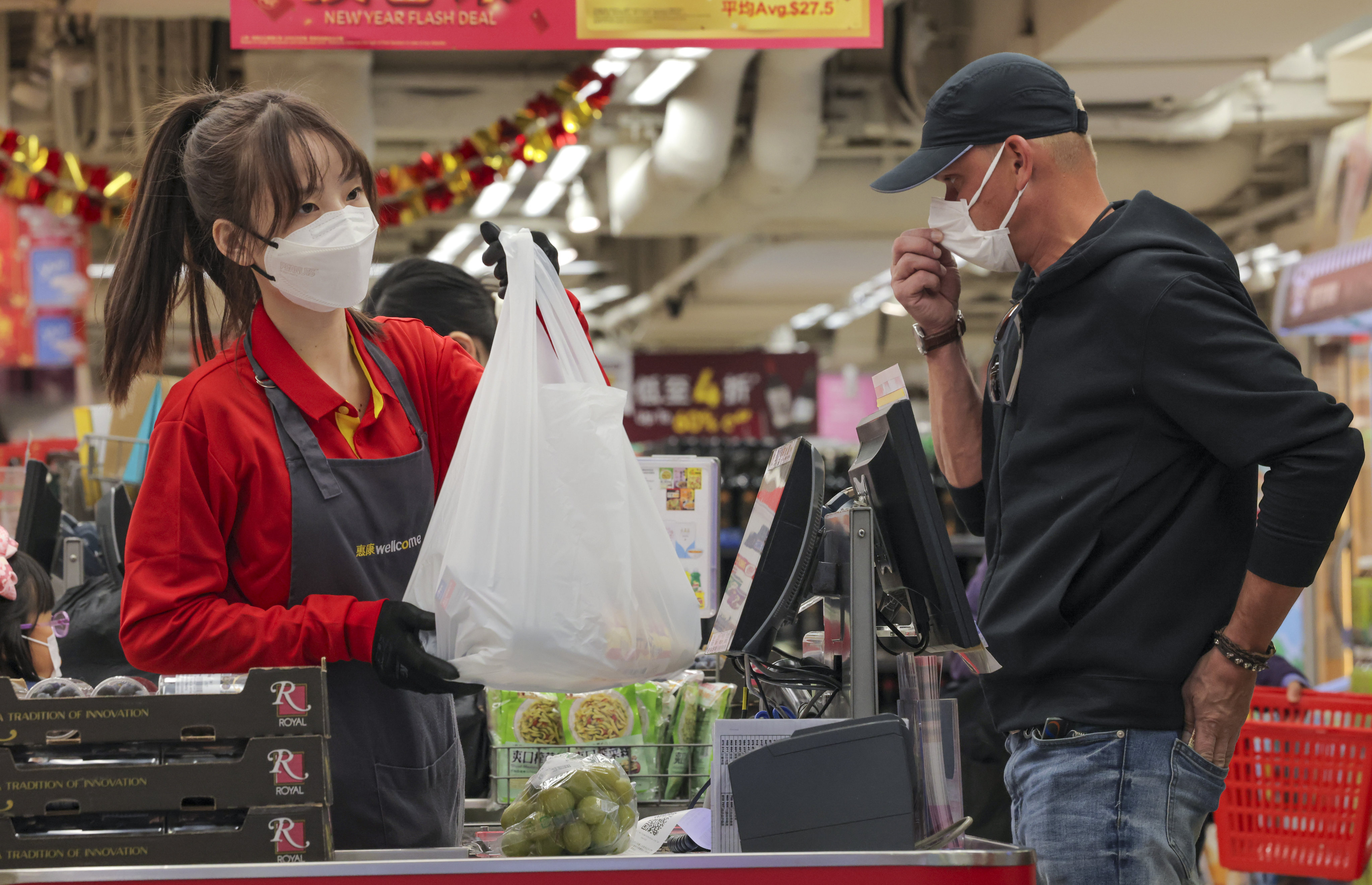 A grocery store cashier in Causeway Bay hands a customer a plastic bag on December 31 last year. Hongkongers have started paying HK$1 for each plastic bag at supermarkets, the first increase in the plastic bag levy in 13 years. Photo: Jelly Tse