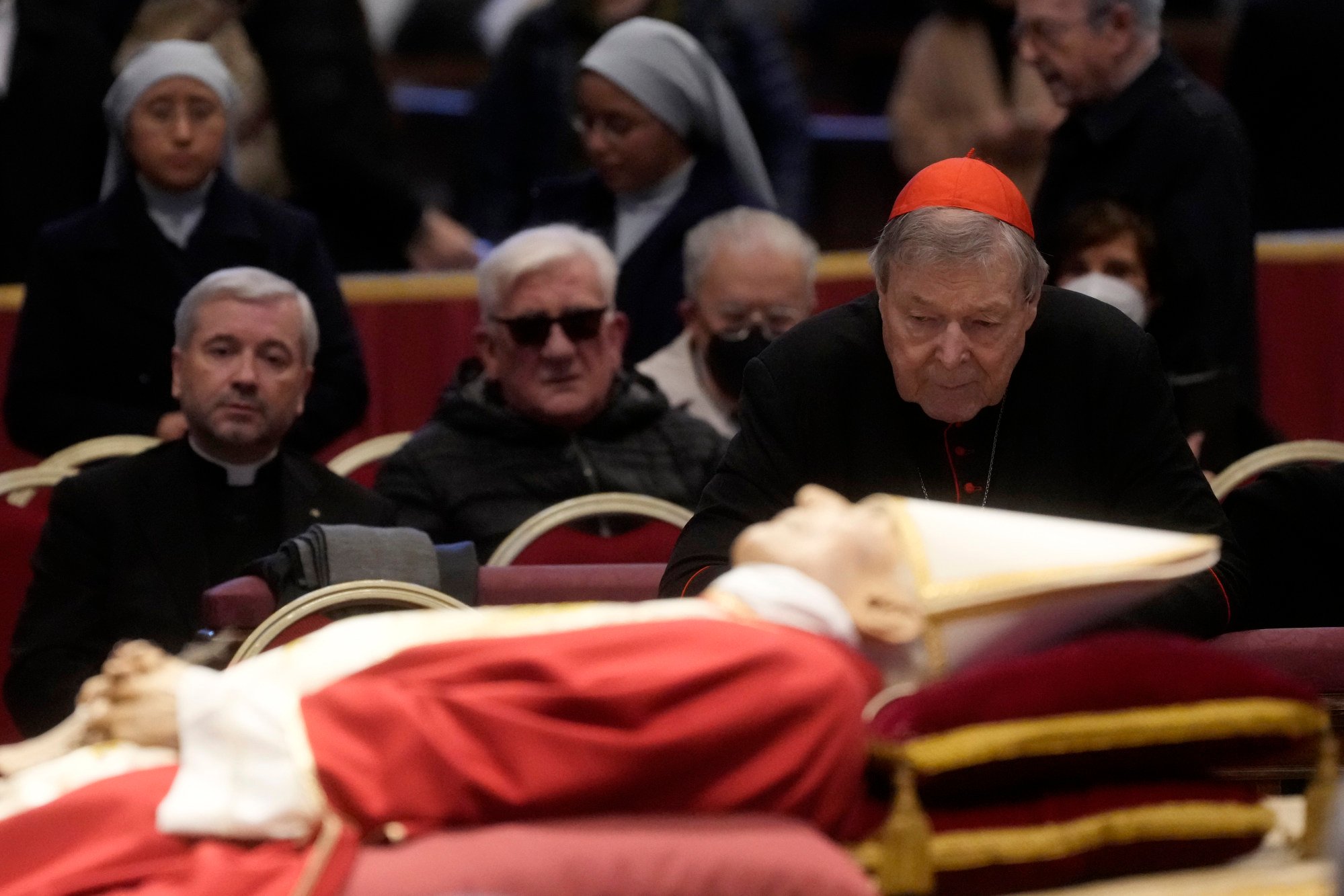Đức Hồng Y Pell (phải) đứng cạnh thi hài của cố Giáo hoàng Bênêđictô XVI đang được quàn bên trong Vương cung thánh đường Thánh Phêrô ở Vatican hồi đầu tháng.  Ảnh: AP