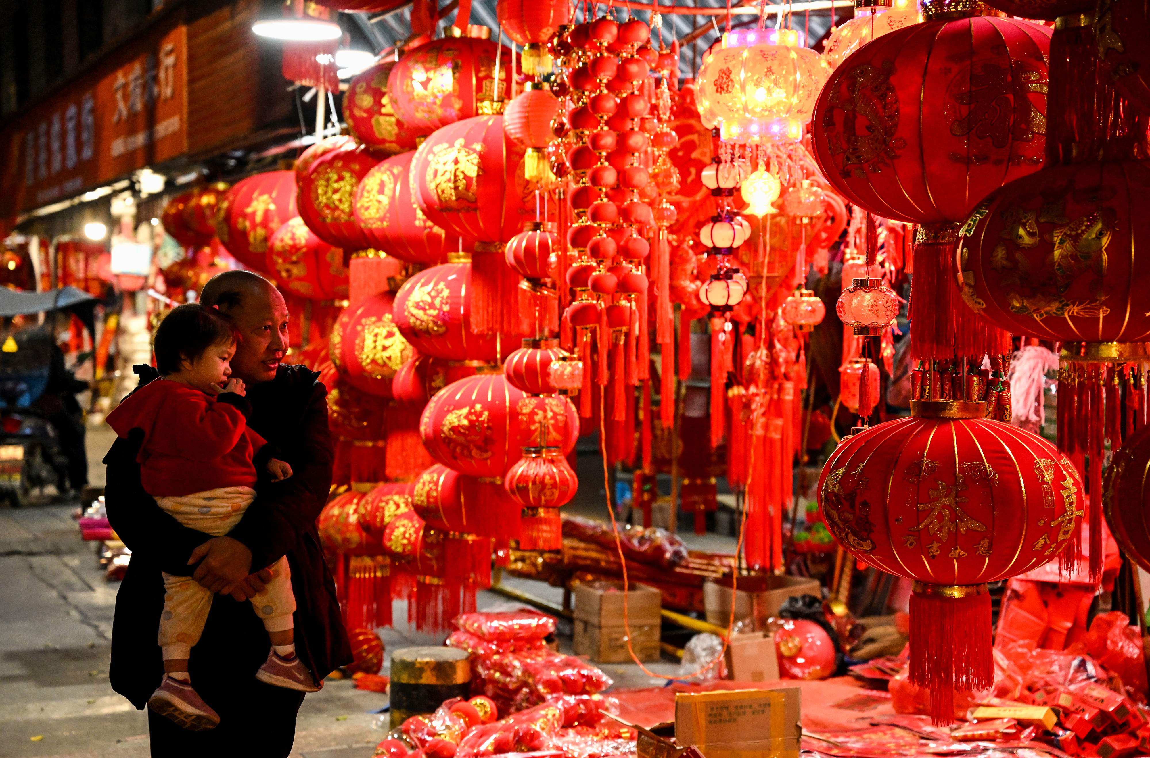 Shoppers walk past Chinese Lunar New Year decorations for sale in the border city of Ruili. Photo: AFP