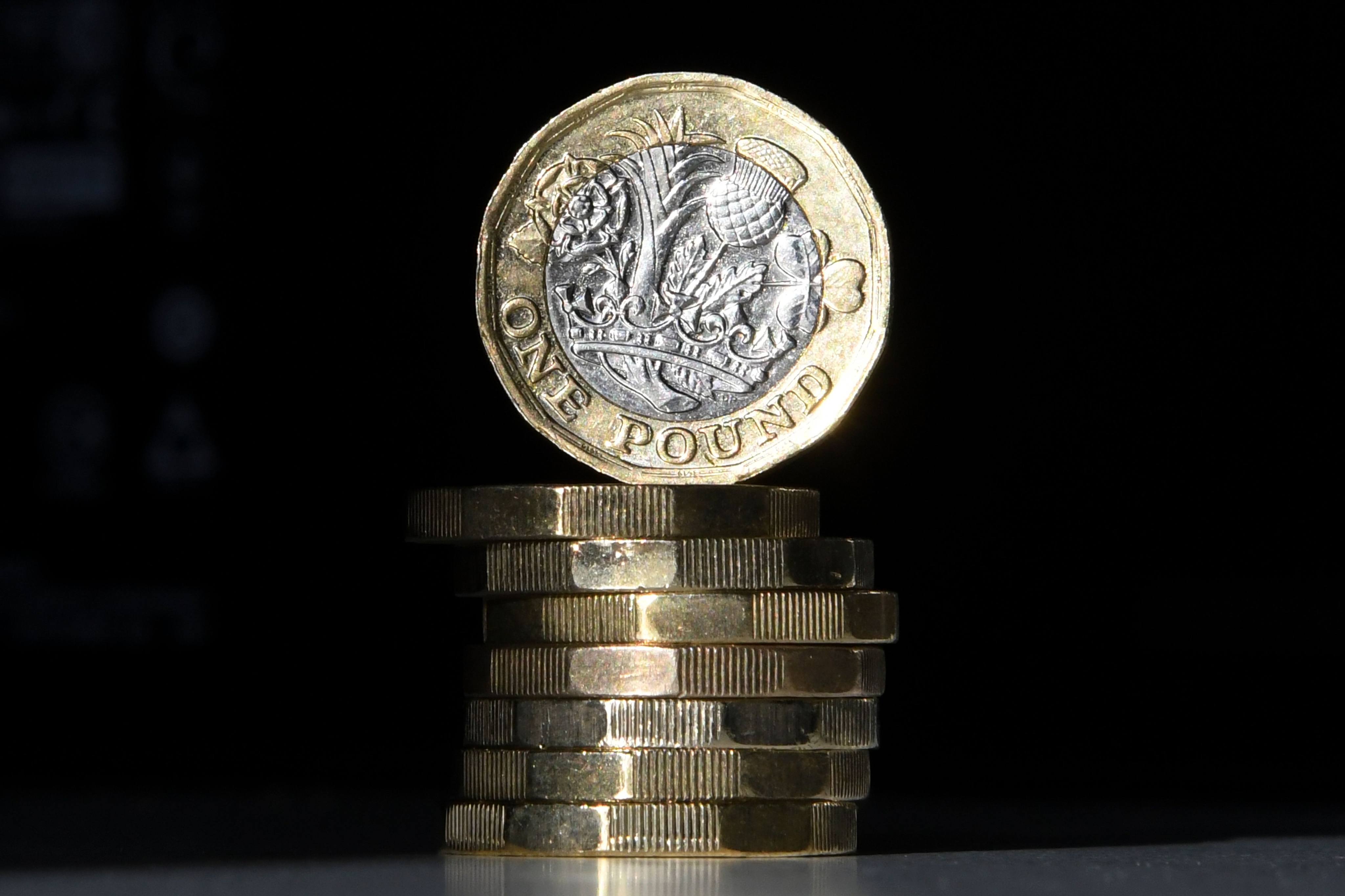 (FILES) This file photo taken on October 05, 2017 shows British one pound sterling coins arranged for a photograph in central London. Britain’s old one-pound coin is being phased out completely on October 15, 2017, but businesses complain they have been given too little time to switch to the new one and many are planning to defy the deadline. / AFP PHOTO / Daniel SORABJI
