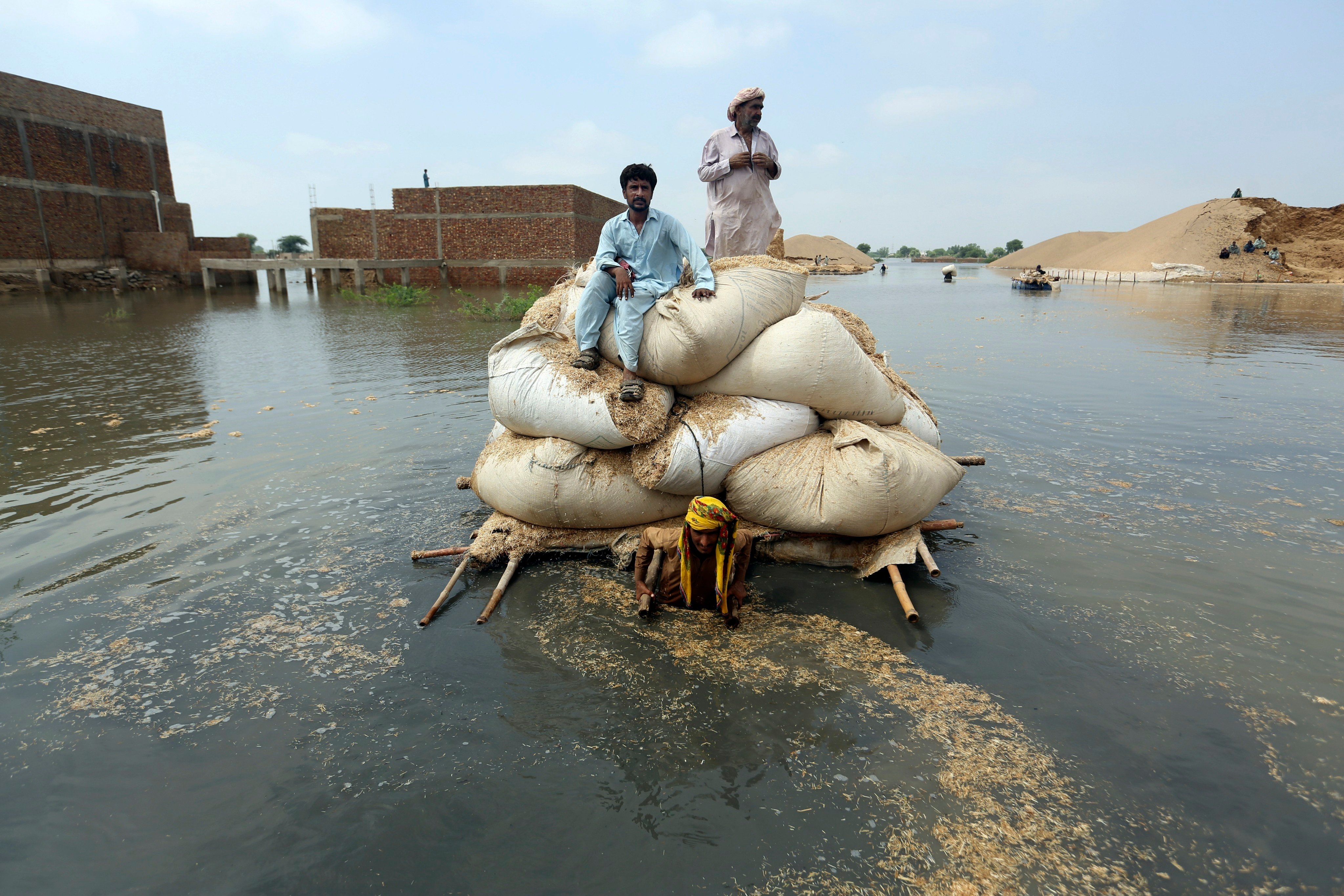 Flood victims from monsoon rain use a makeshift barge to carry hay for cattle, in Jaffarabad, in Pakistan’s southwestern Baluchistan province, on September 5, 2022. The flooding is just a preview of the climate consequences that are now impossible to avoid. Photo: AP