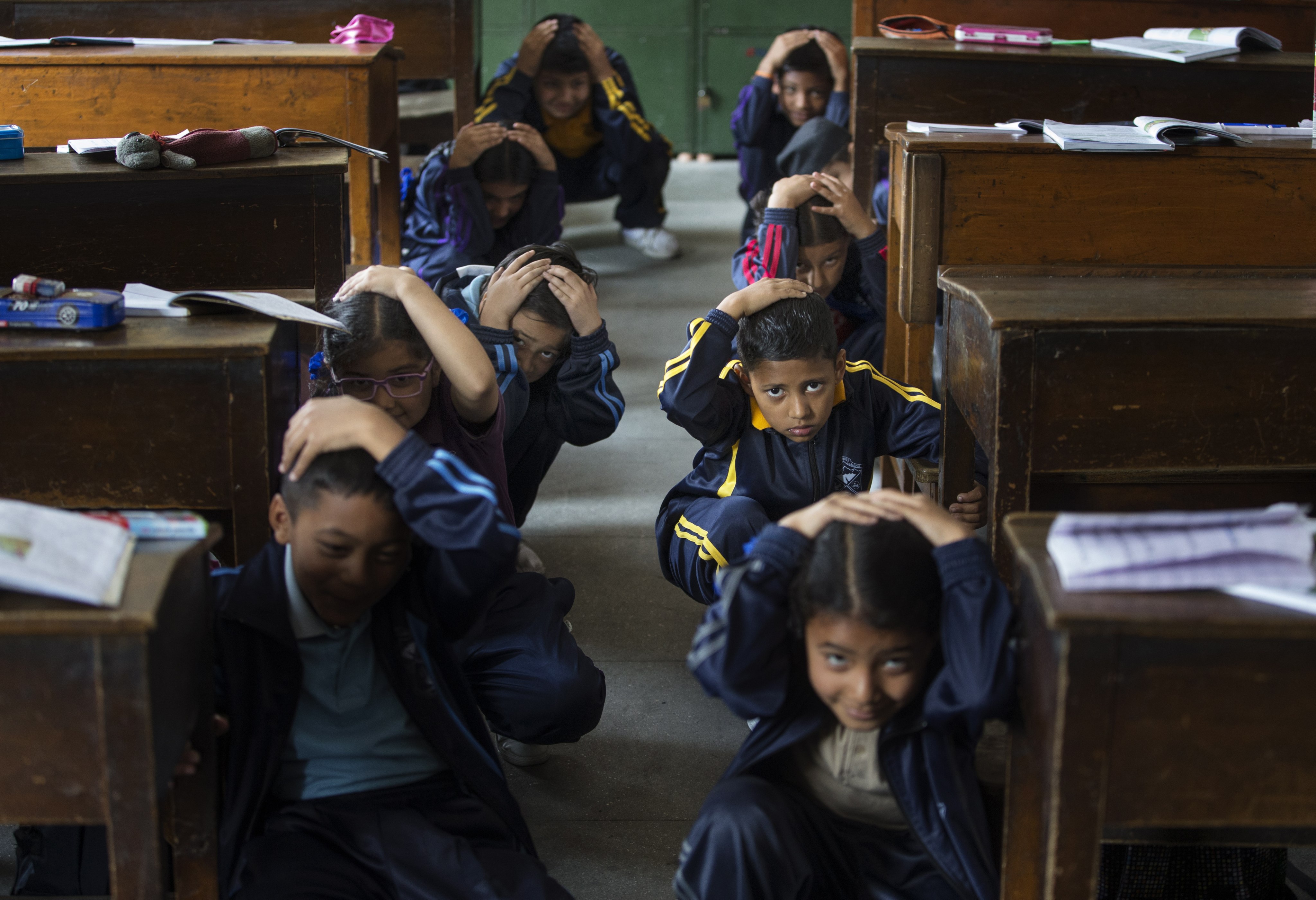 Nepalese school children crouch near their desks during an earthquake drill. The nation often experiences quakes; in 2015 around 9,000 people died in one. File photo:  EPA-EFE